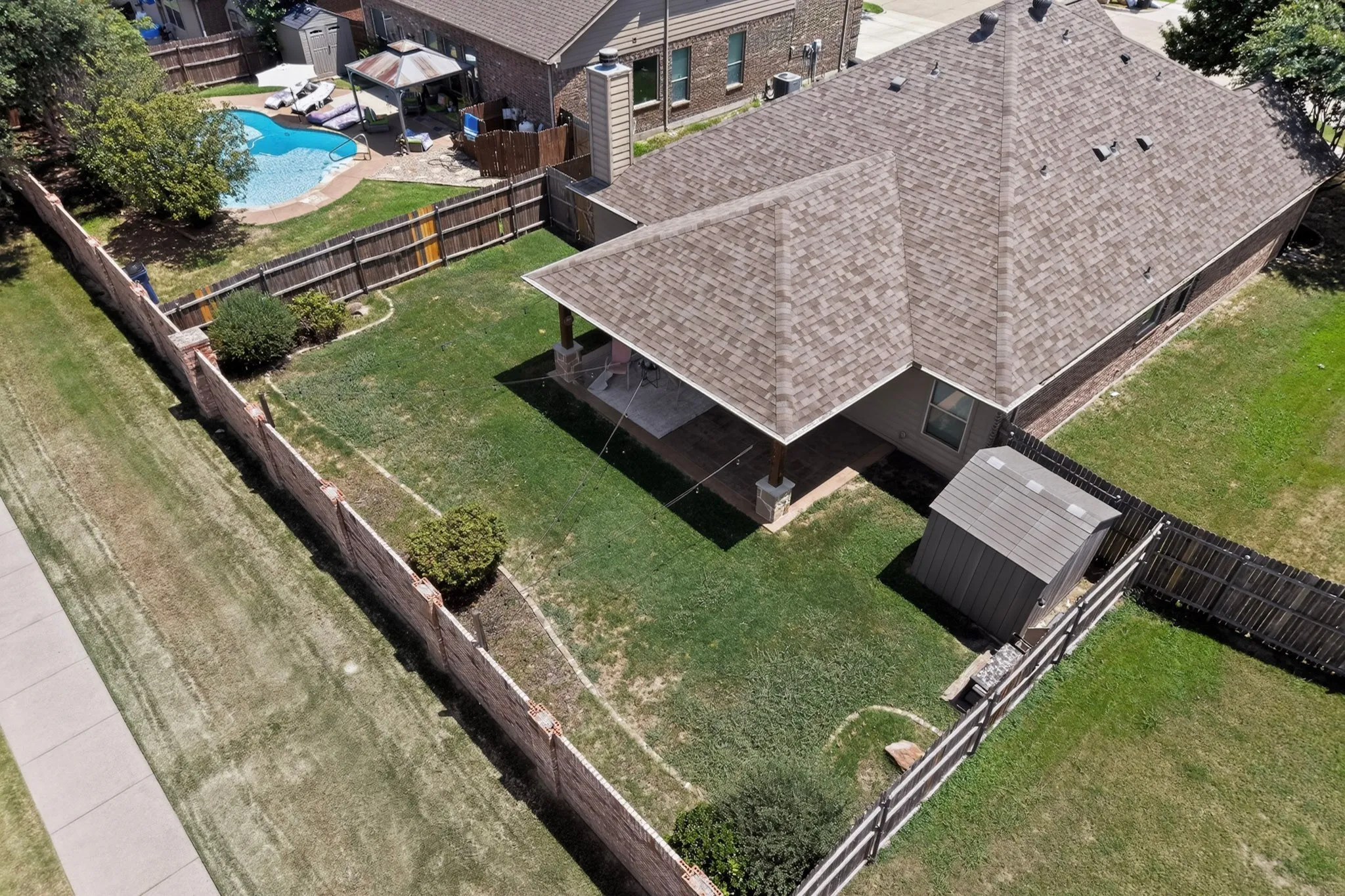 Expansive backyard featuring a covered patio, a storage shed, and perimeter fencing