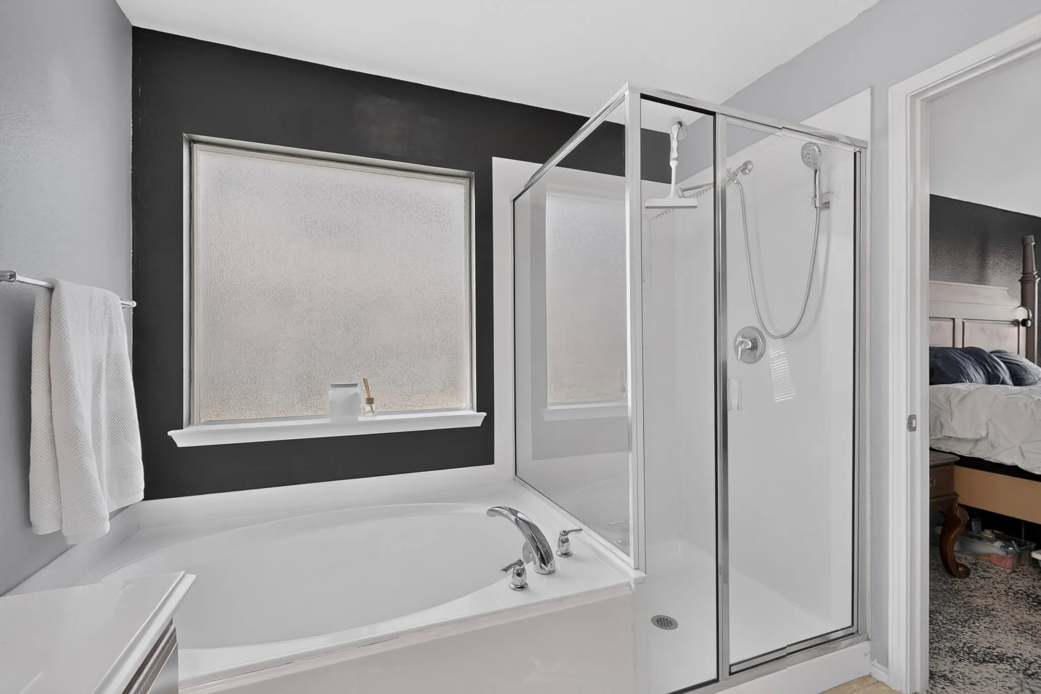 Alcove bathtub with deck-mounted faucet, separate shower enclosure with glass panels, and a frosted privacy window