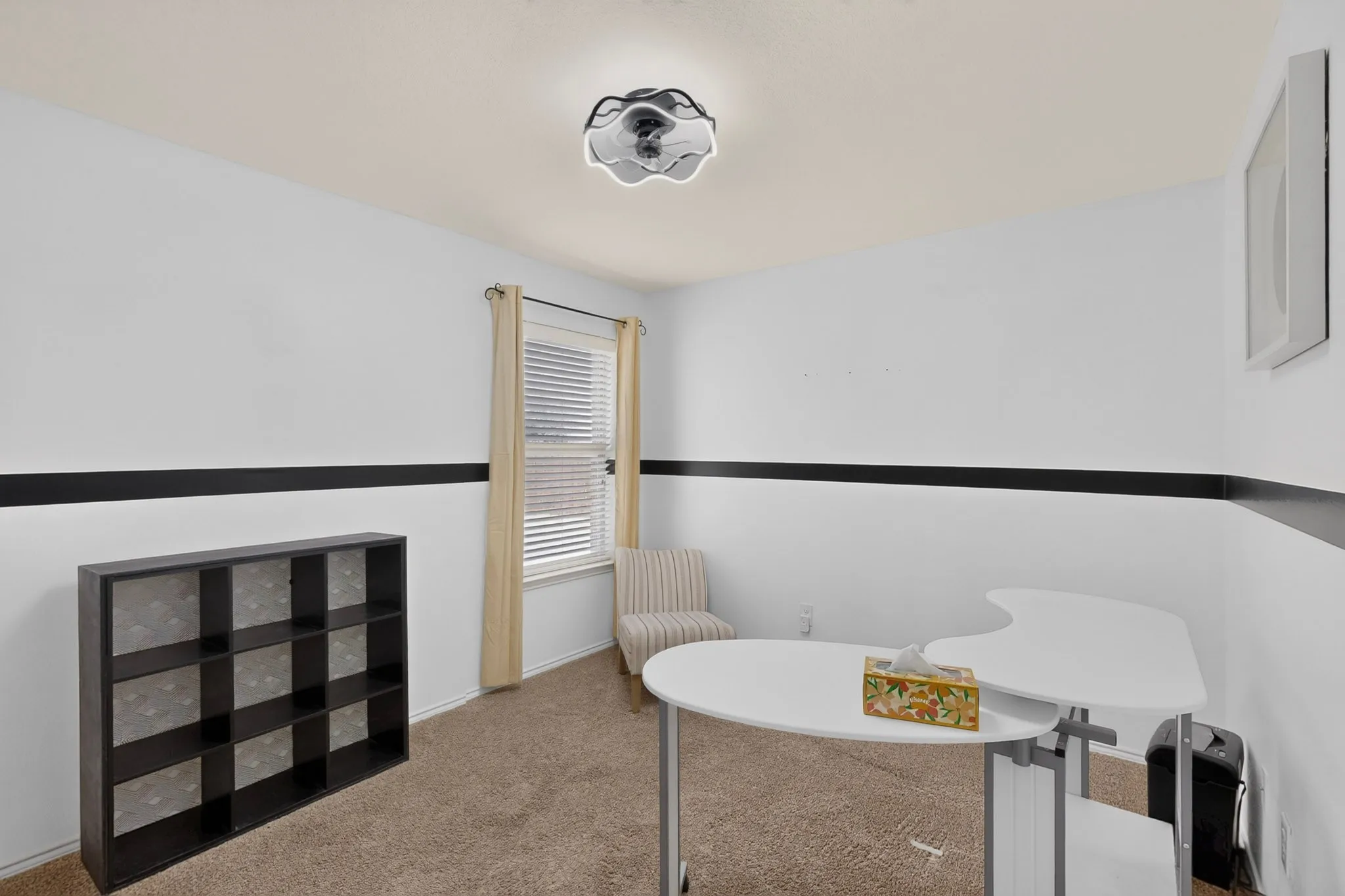 Neutral wall colors with a decorative black stripe, carpet flooring, window with blinds and drapes, and an overhead light fixture