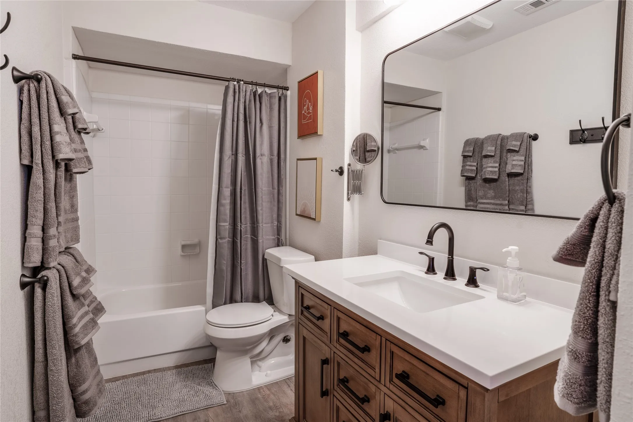 White vanity with a rectangular undermount sink, dark bronze-finish faucet, and a large framed mirror