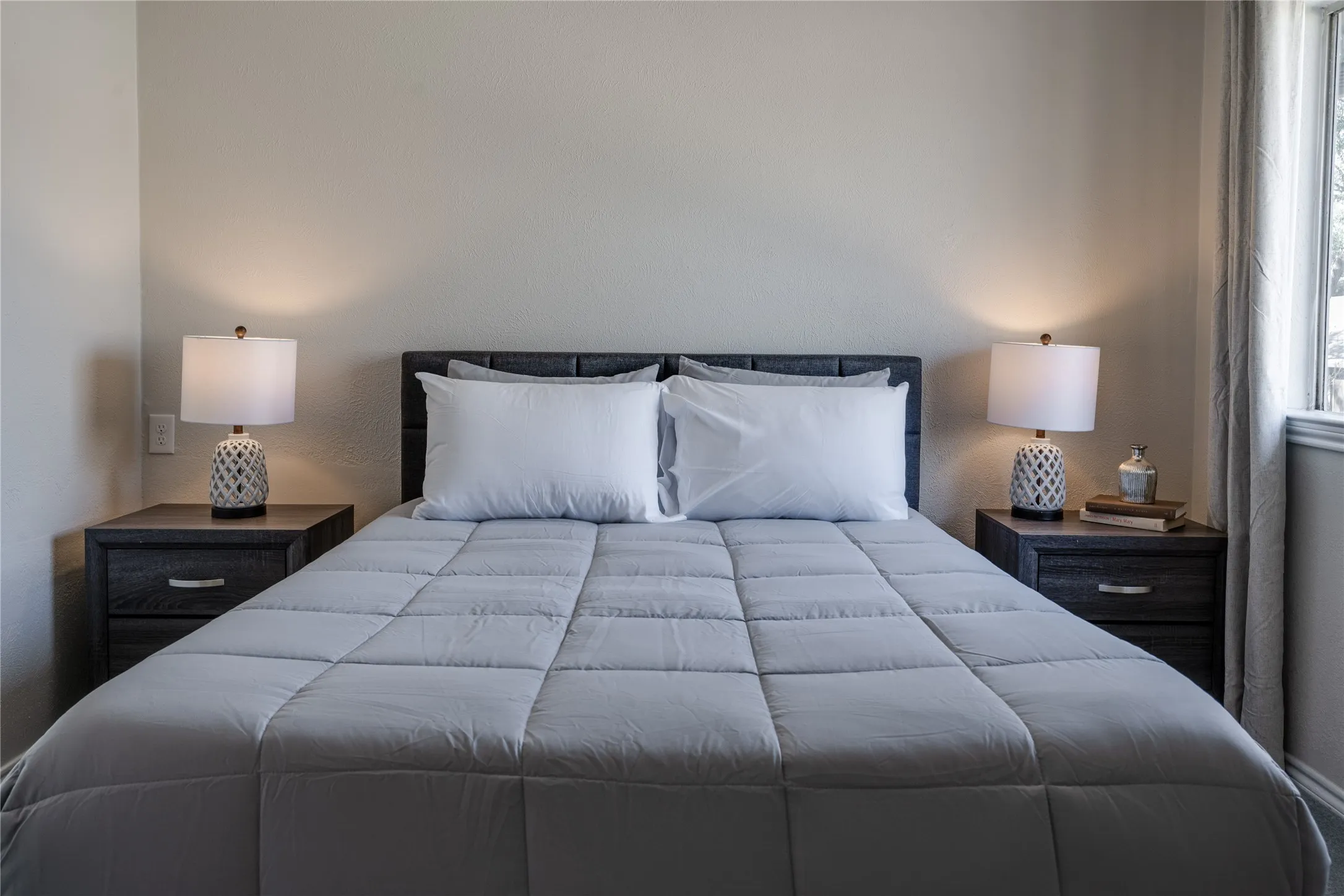 Textured headboard, window with drapes, and neutral wall tones