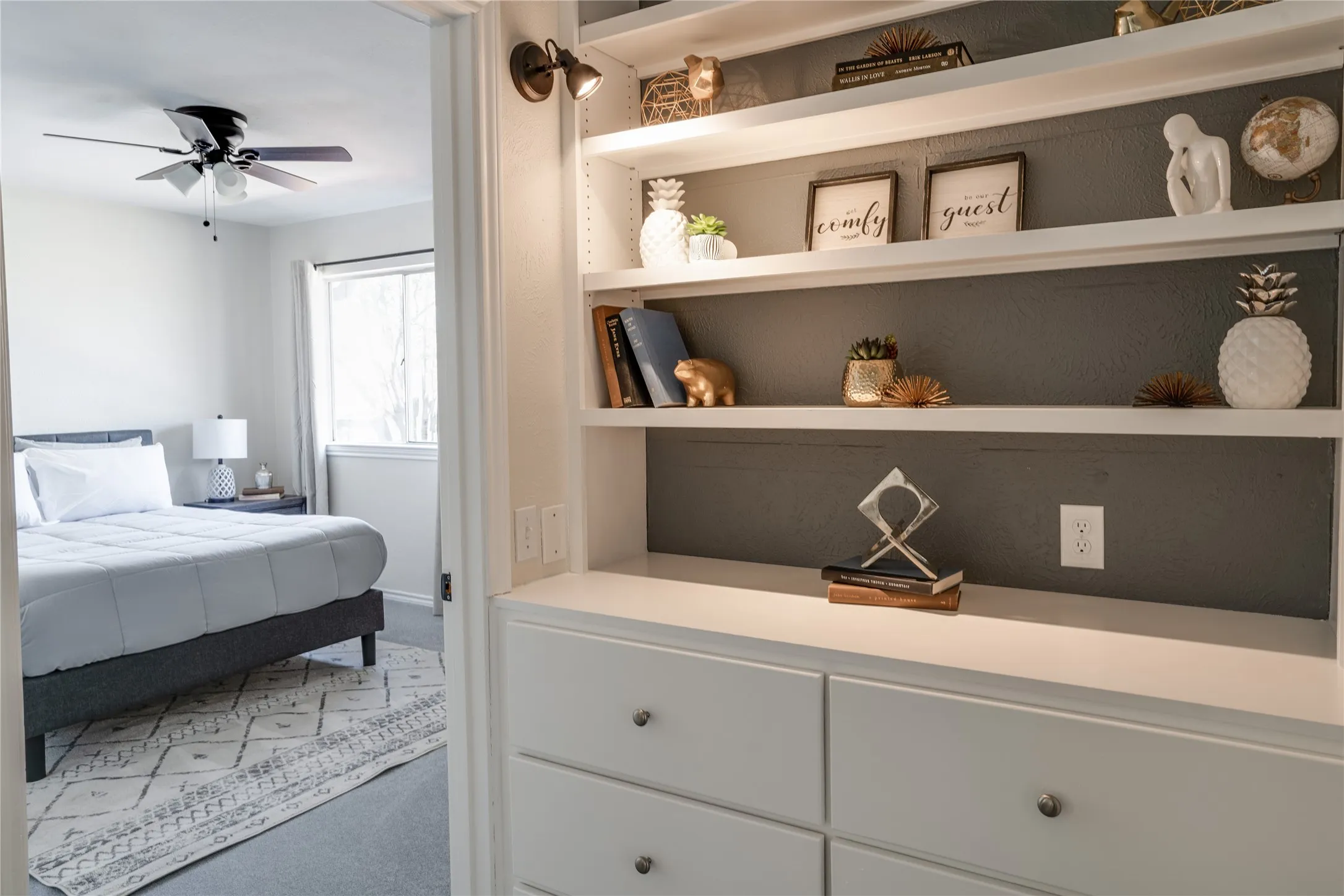Built-in shelving with integrated lighting, a ceiling fan, and a window with natural light