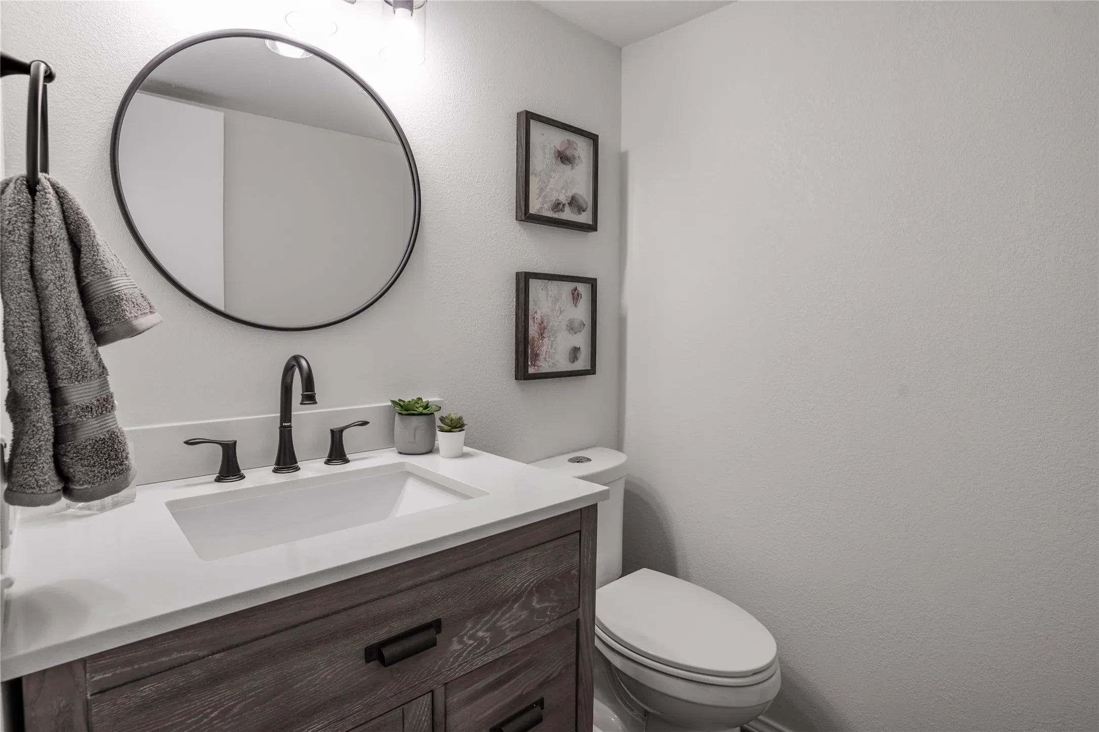Wood-finish vanity with an integrated sink, white countertop, and matte black fixtures