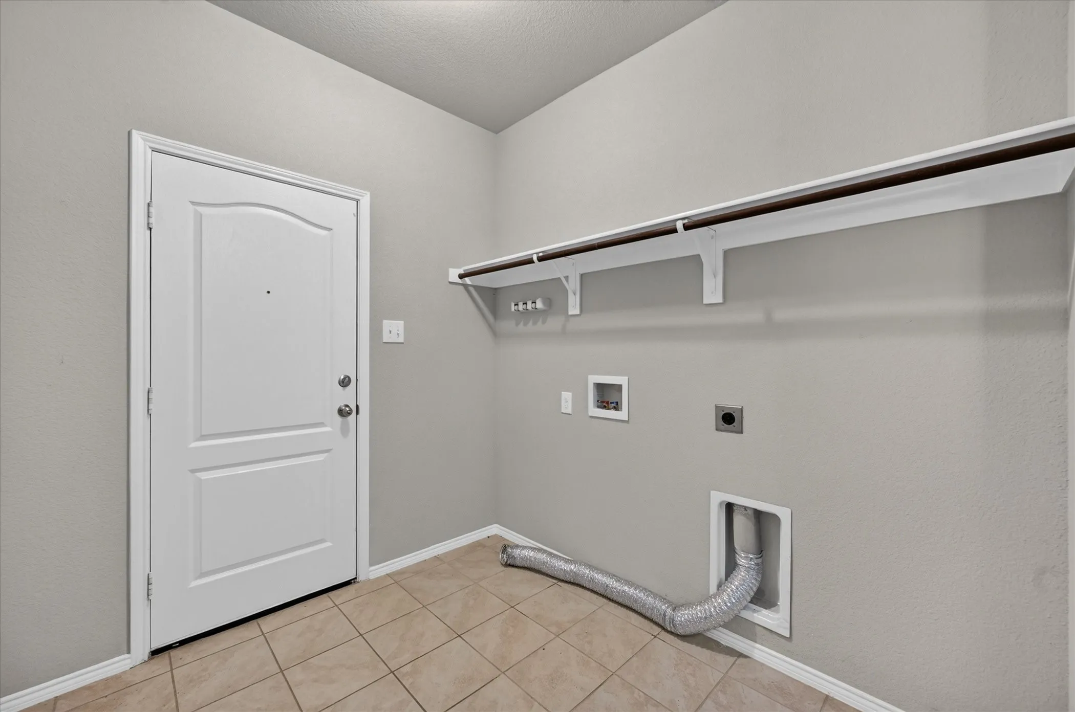 Utility room with tile flooring, neutral wall color, and a built-in hanging rod
