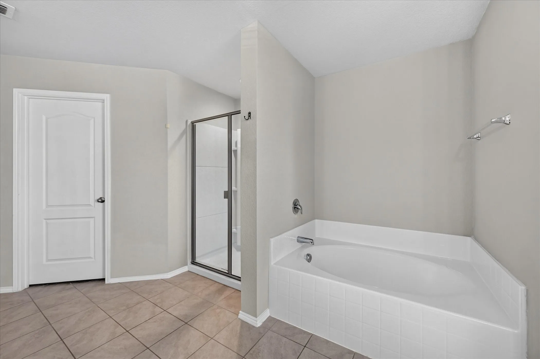 Built-in soaking tub, separate shower enclosure with glass door, and tiled flooring