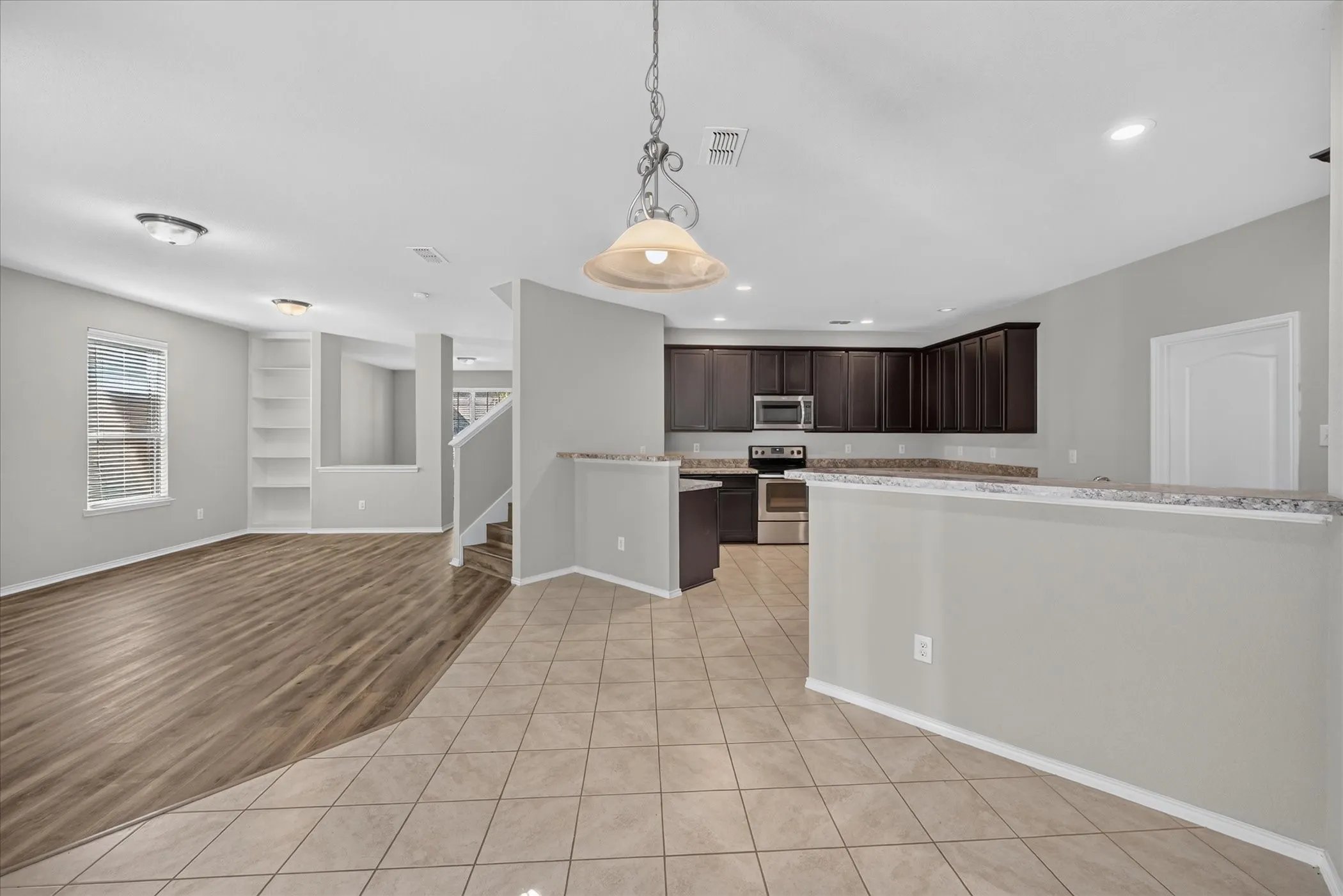 Kitchen featuring dark cabinetry, light-toned countertops, a stainless steel dishwasher, and recessed lighting
