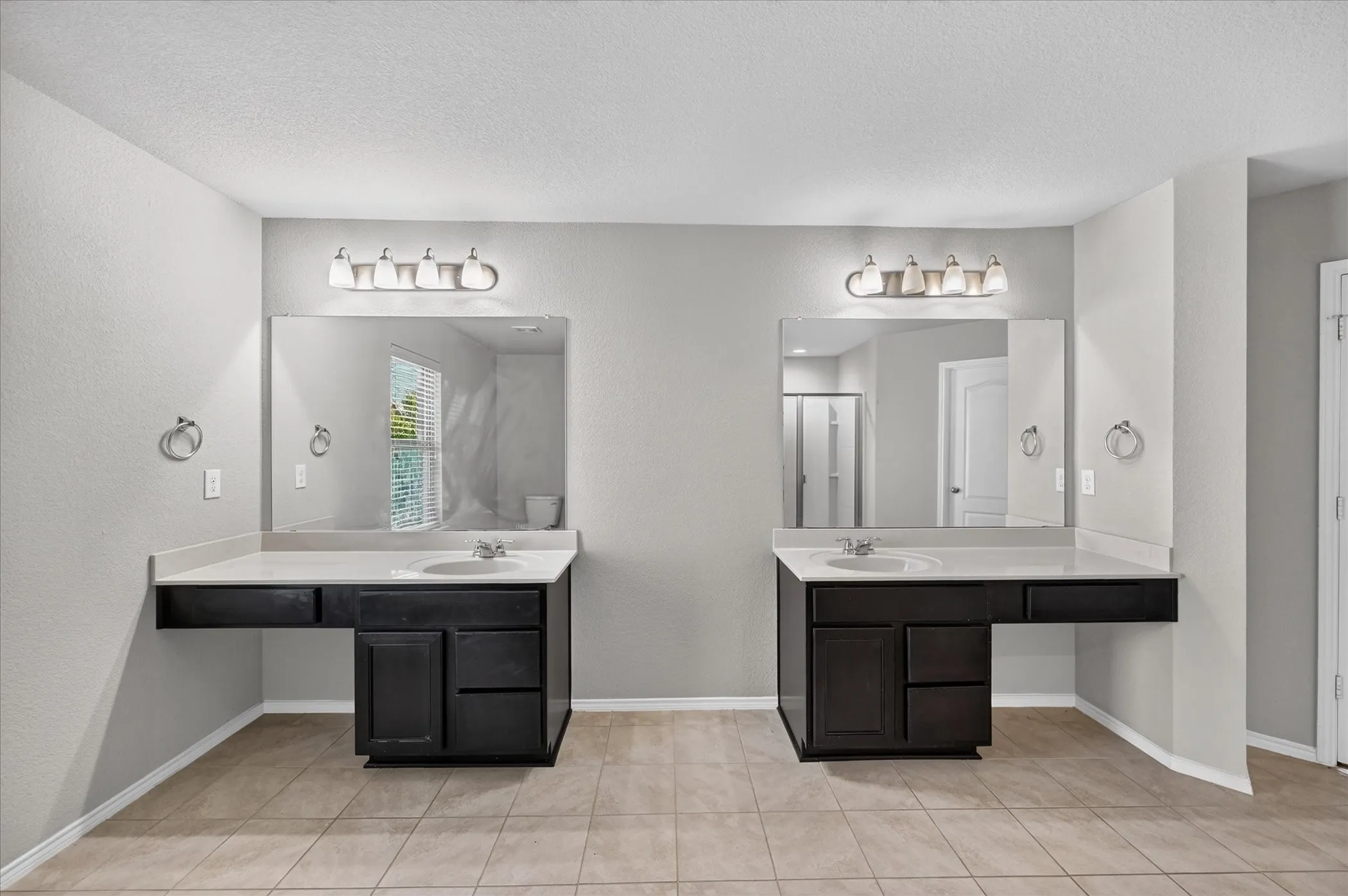 Dual vanity sinks with dark wood-finish cabinetry, light countertops, and individual mirrors