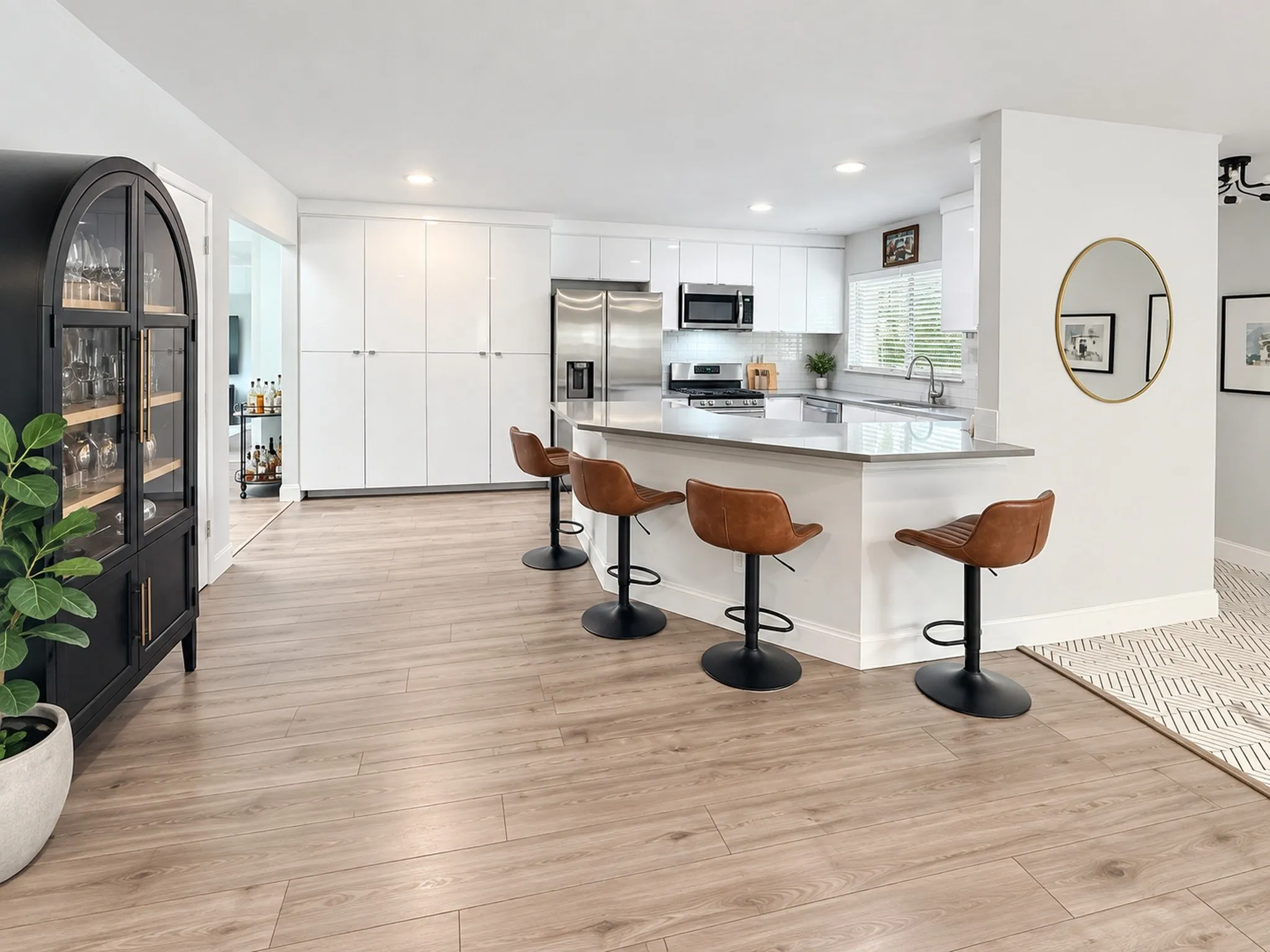 Kitchen featuring a multi-functional island with a countertop, stainless steel appliances, white cabinetry, and wood-finish flooring