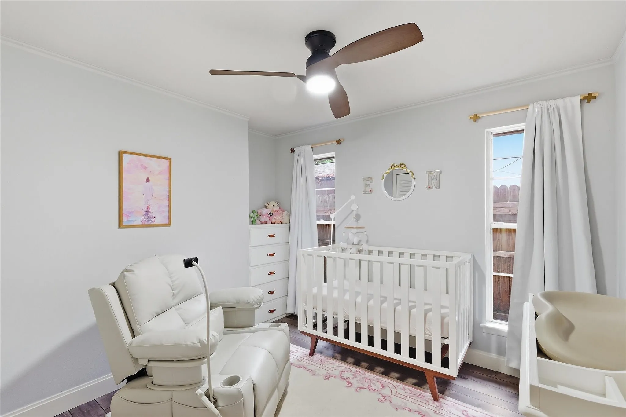  Crown molding, ceiling fan, and two windows with white curtains