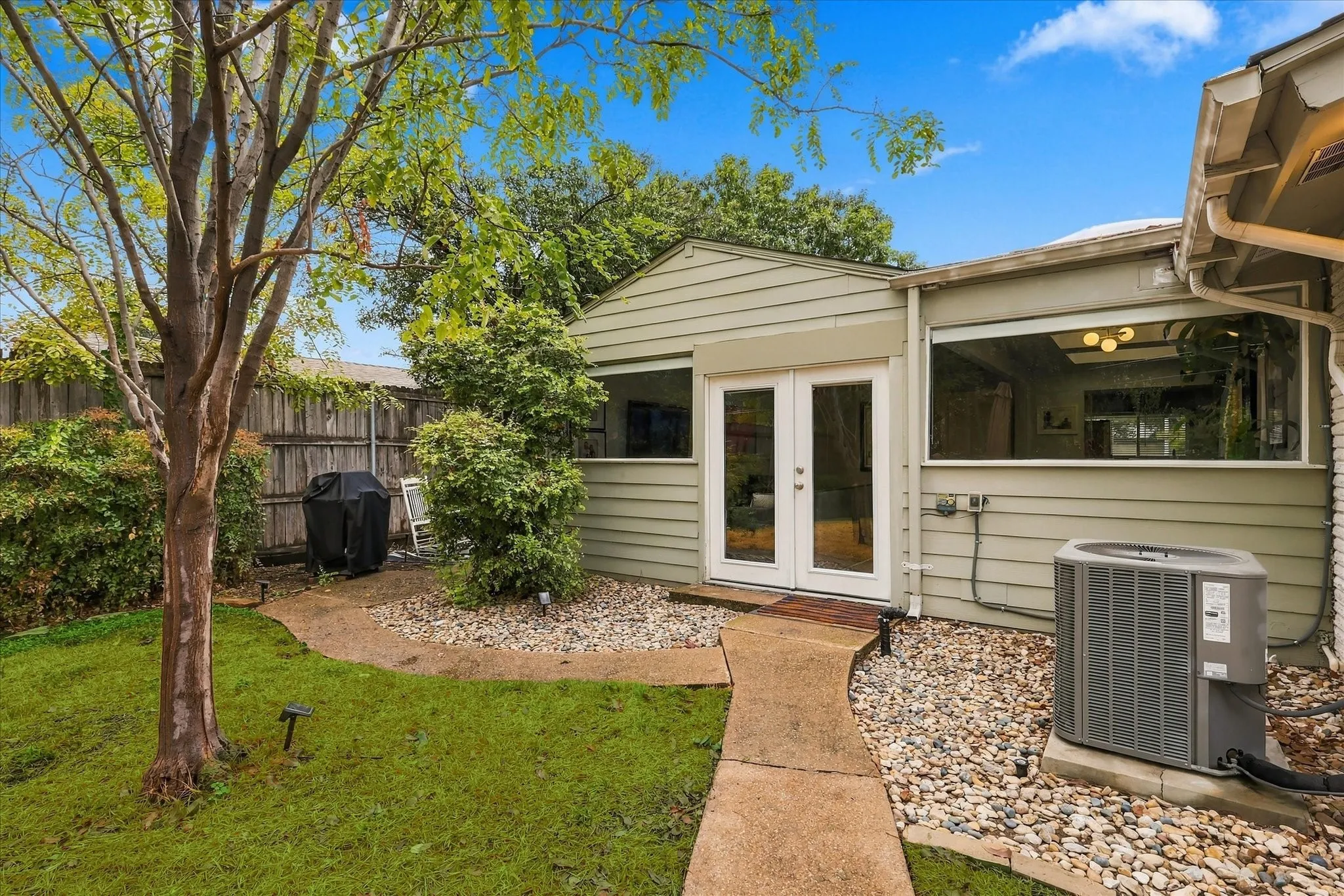Rear exterior with double-pane glass doors, horizontal siding, and an air conditioning unit