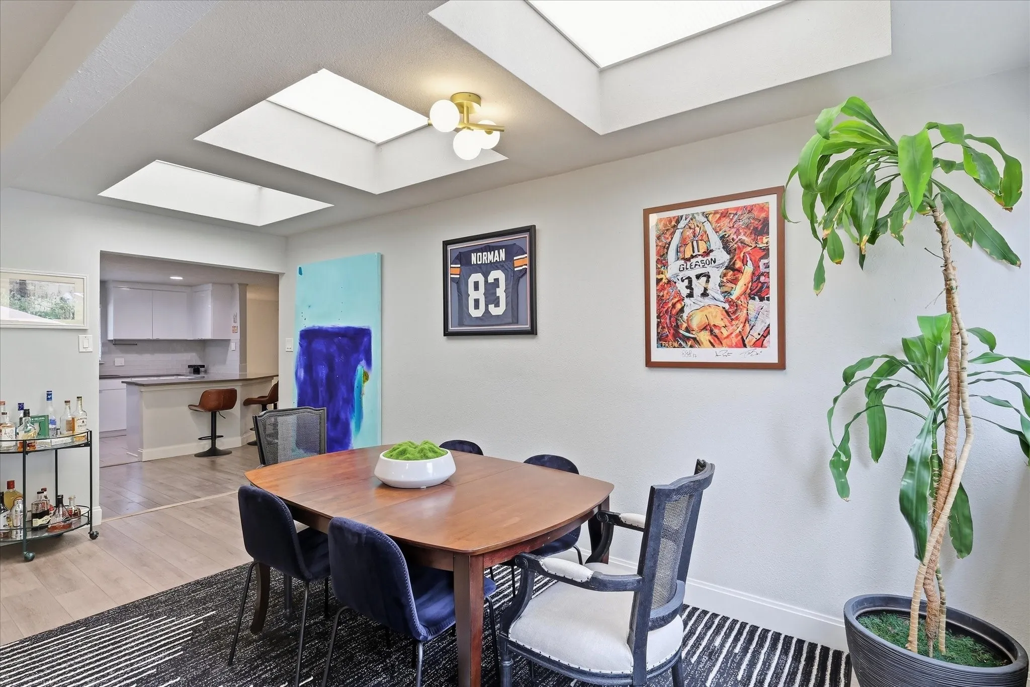 Dining area with multiple skylights, overhead lighting fixture, and light wood-finish flooring