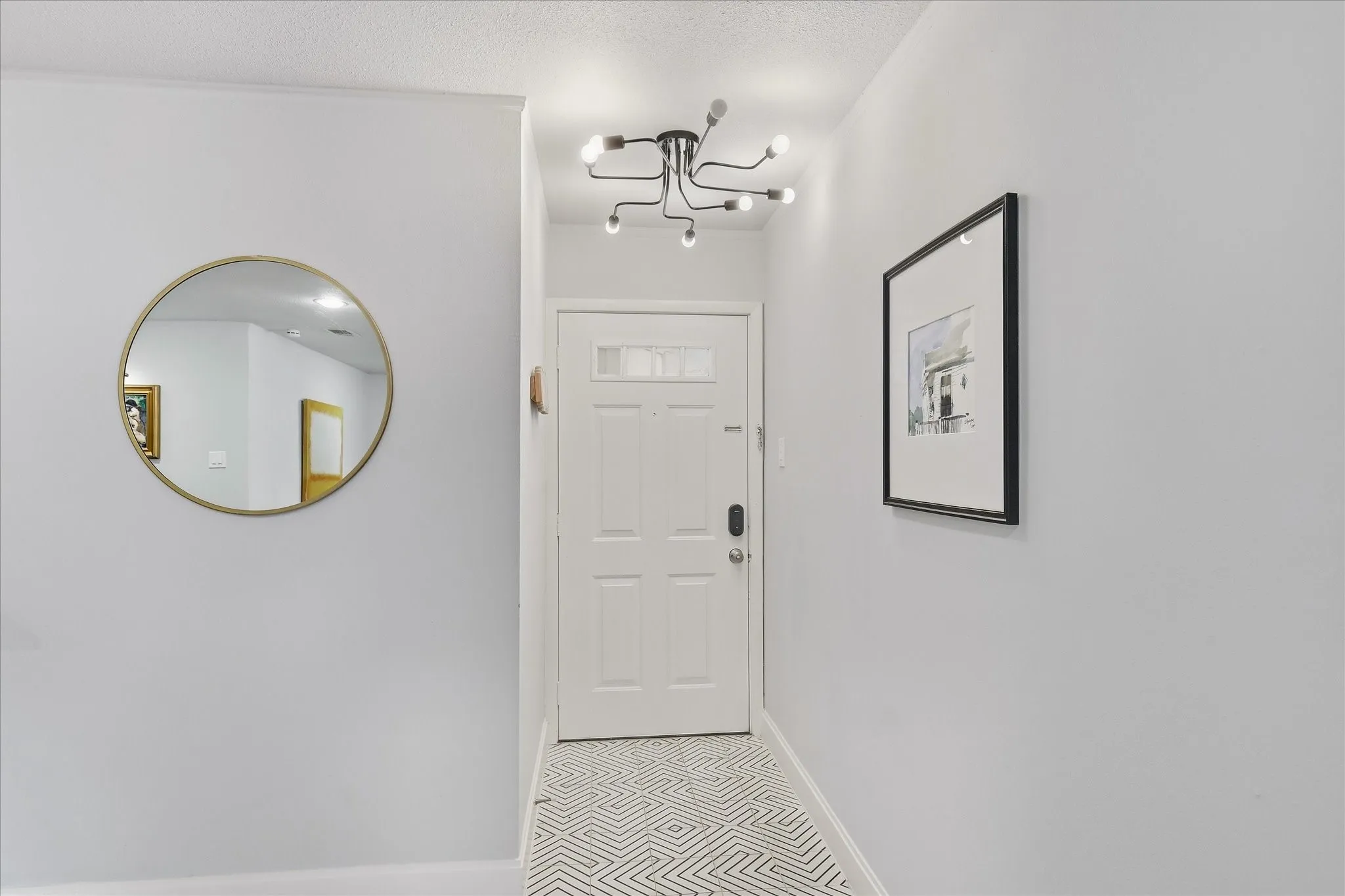 White paneled entry door, patterned tile flooring, and a contemporary ceiling-mounted light fixture