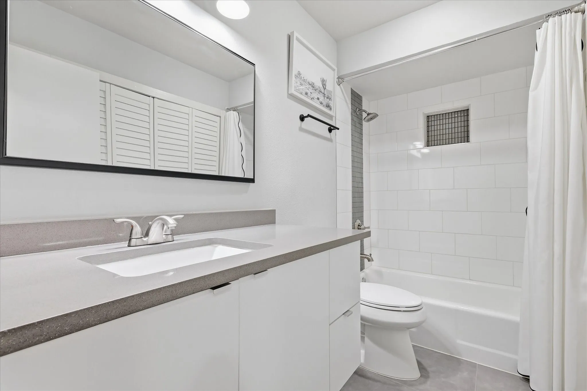 Recessed lighting illuminates 2nd bathroom with a white vanity featuring a rectangular integrated sink and a gray quartz countertop