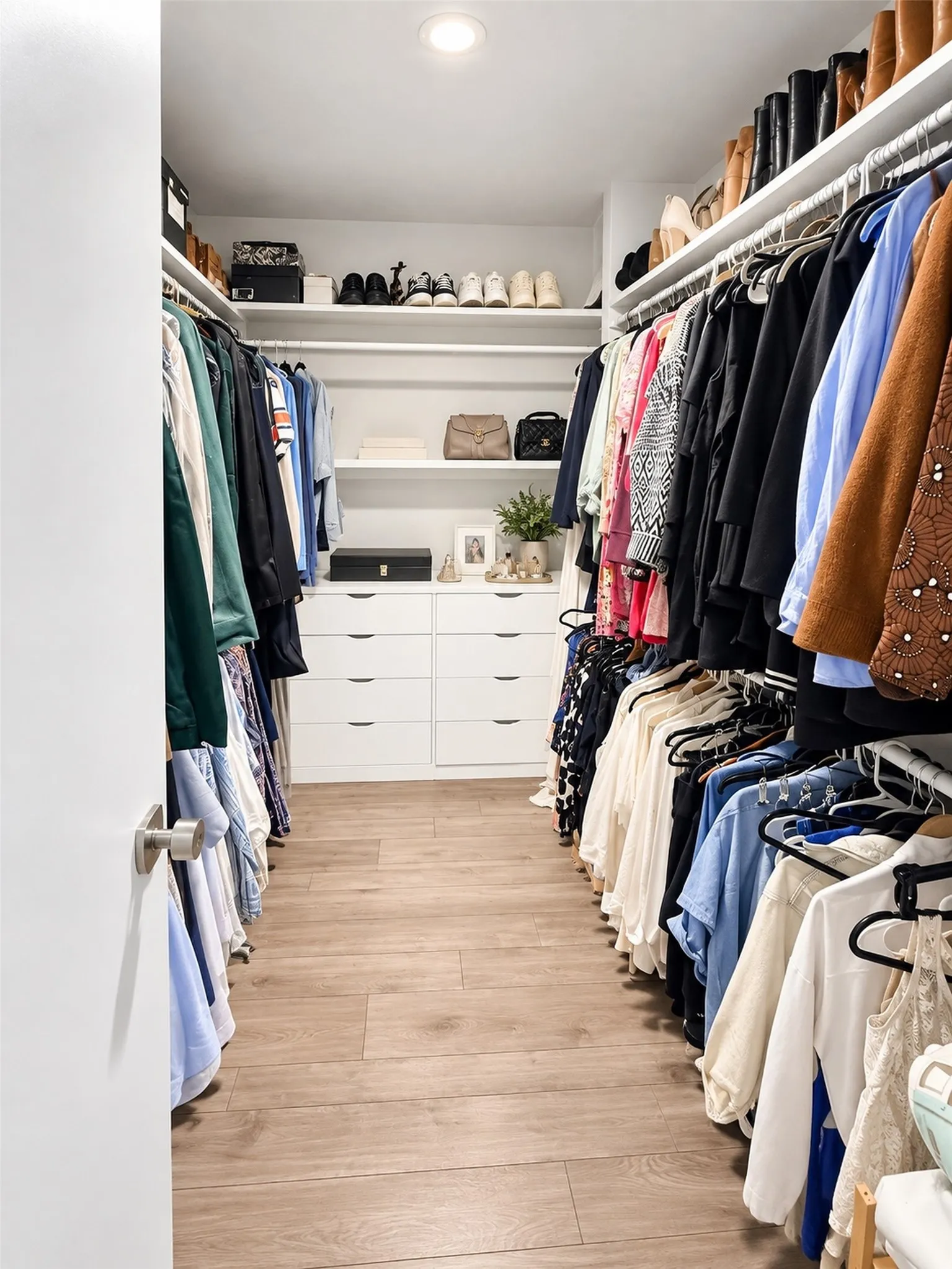 Walk-in closet, hanging rods, recessed lighting, and faux wood-finish flooring