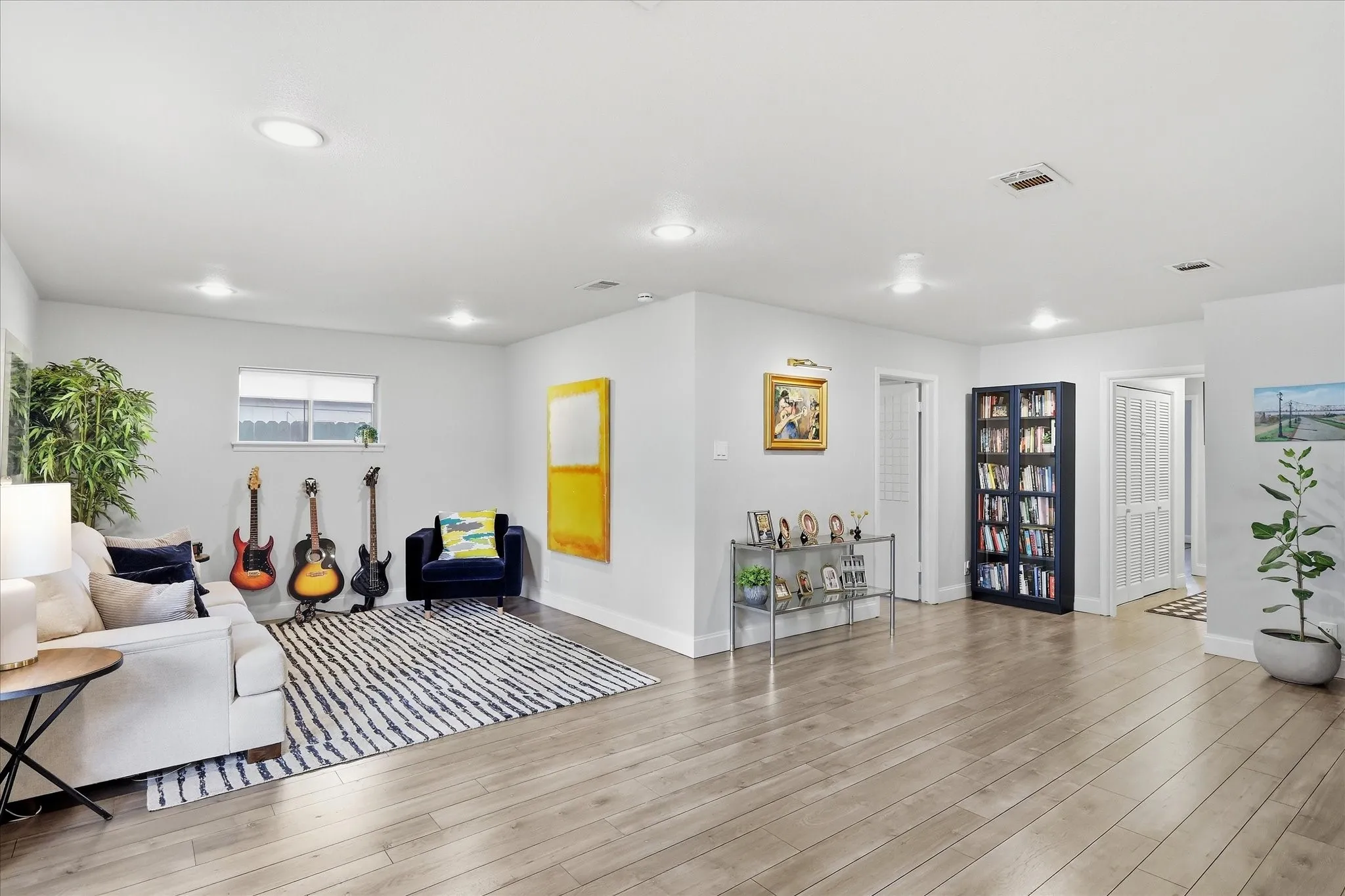 Recessed lighting illuminates this expansive space featuring faux wood-finish flooring and light-toned walls