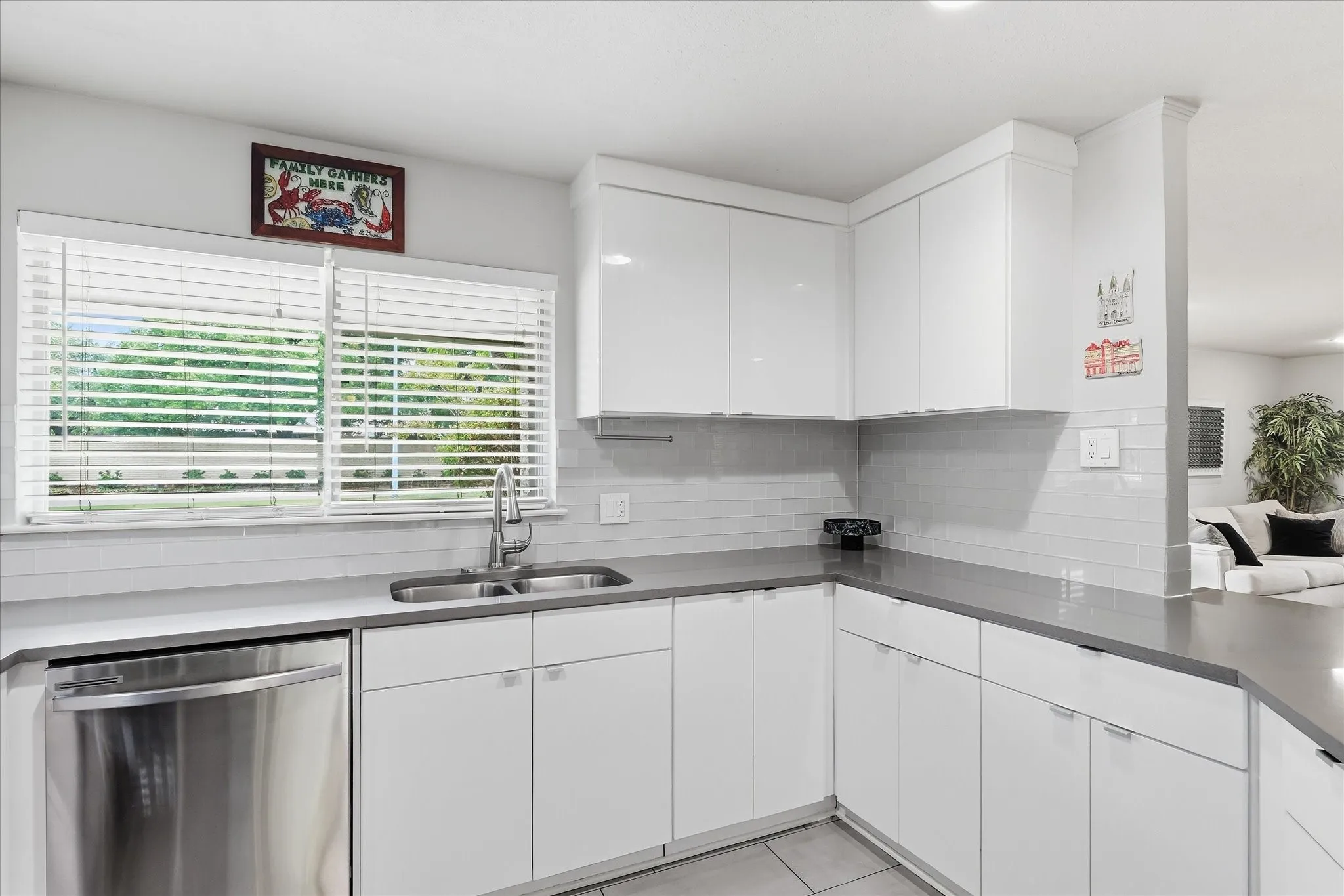 White flat-panel cabinetry, stainless steel dishwasher, undermount double-basin sink, gray quartz countertops, and white subway tile backsplash