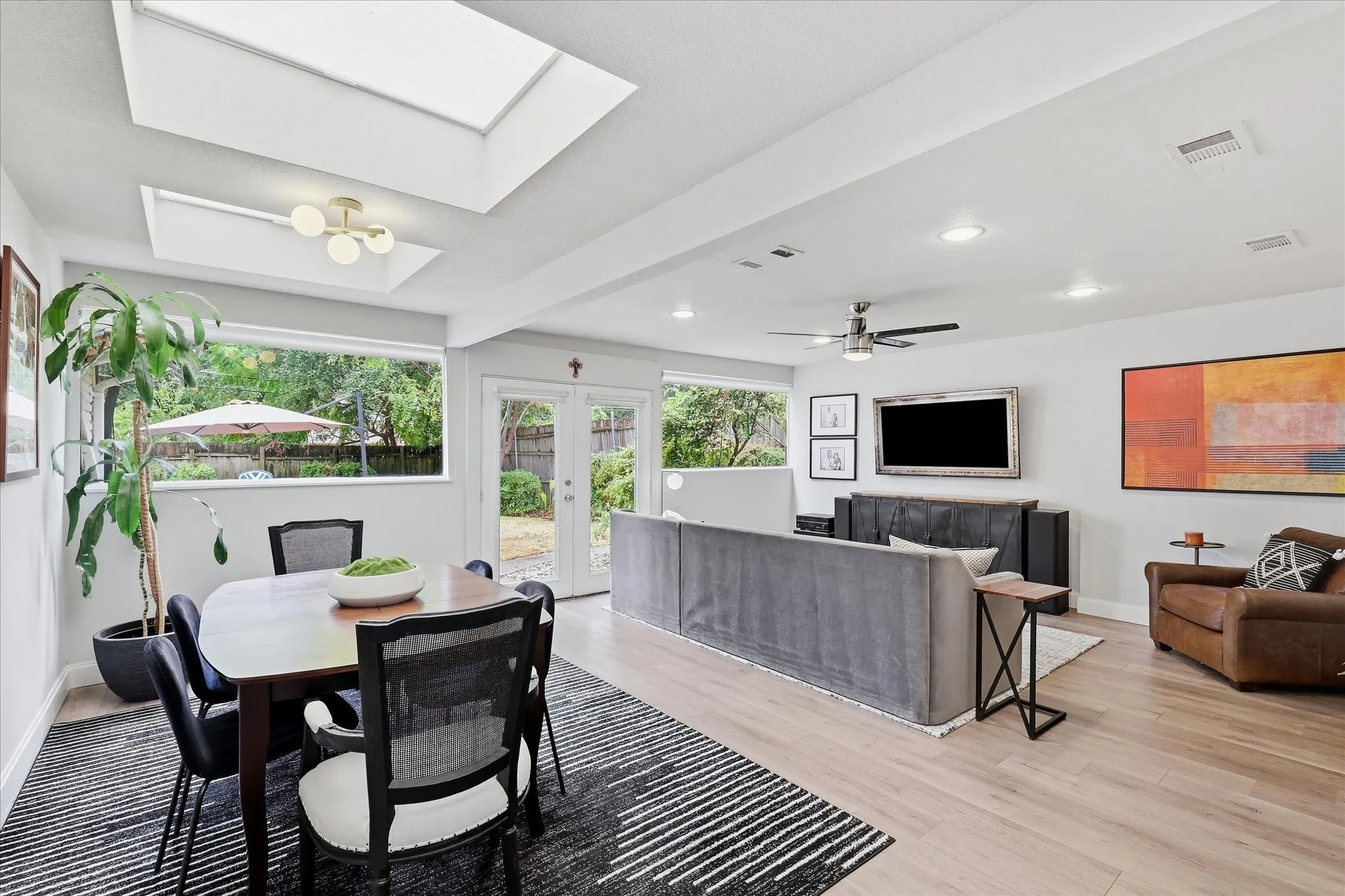 Recessed lighting, skylights, wood-finish flooring, a ceiling fan, and French doors