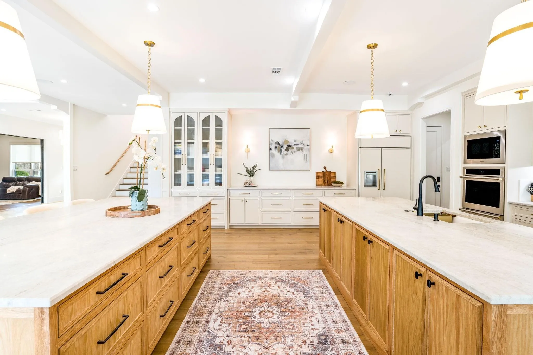 Dual kitchen islands with light-toned countertops, wood-finish cabinetry, and contemporary pendant lighting