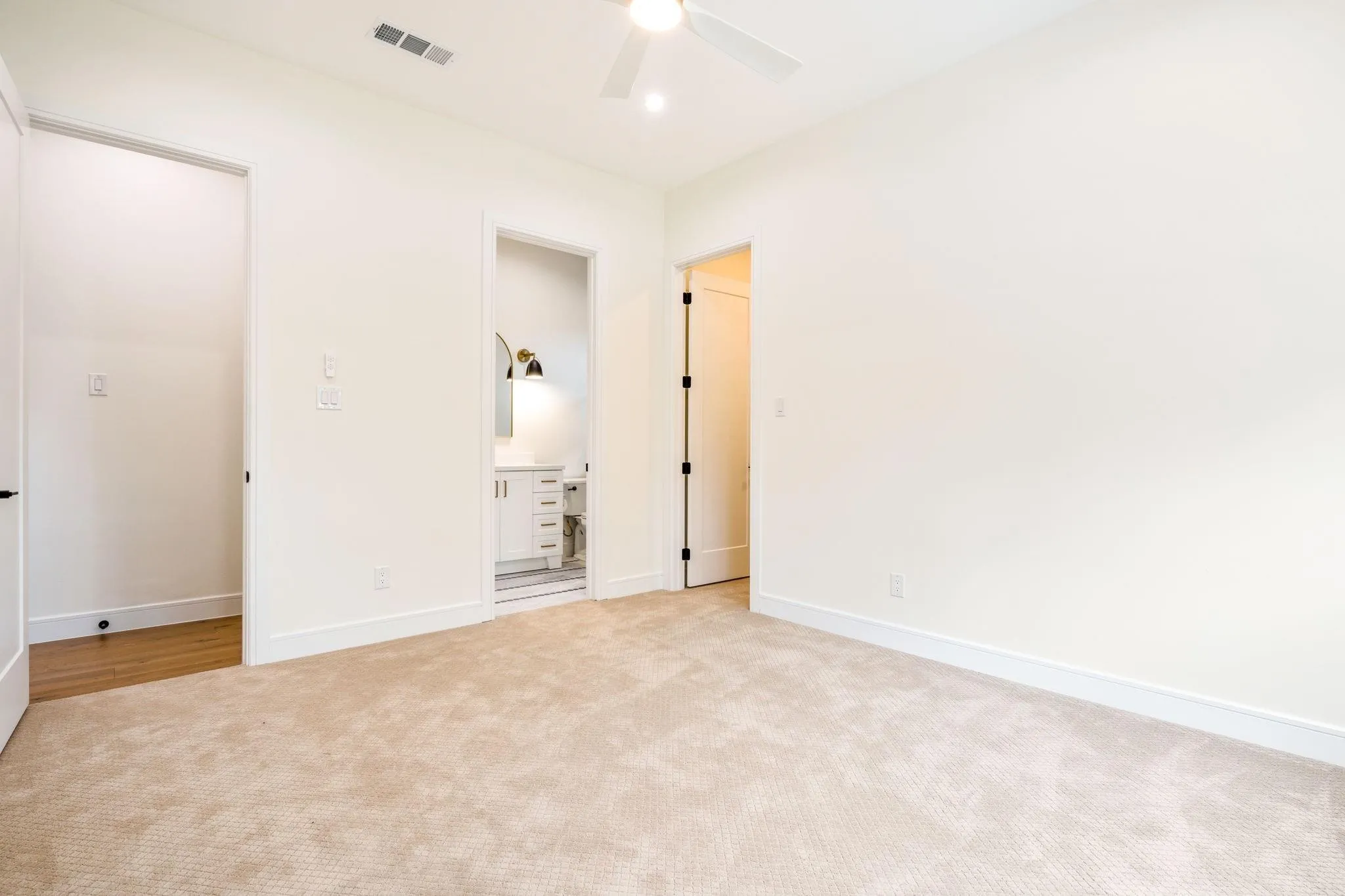 Plush carpet flooring in a neutral tone, ceiling fan with integrated lighting, and a white interior door