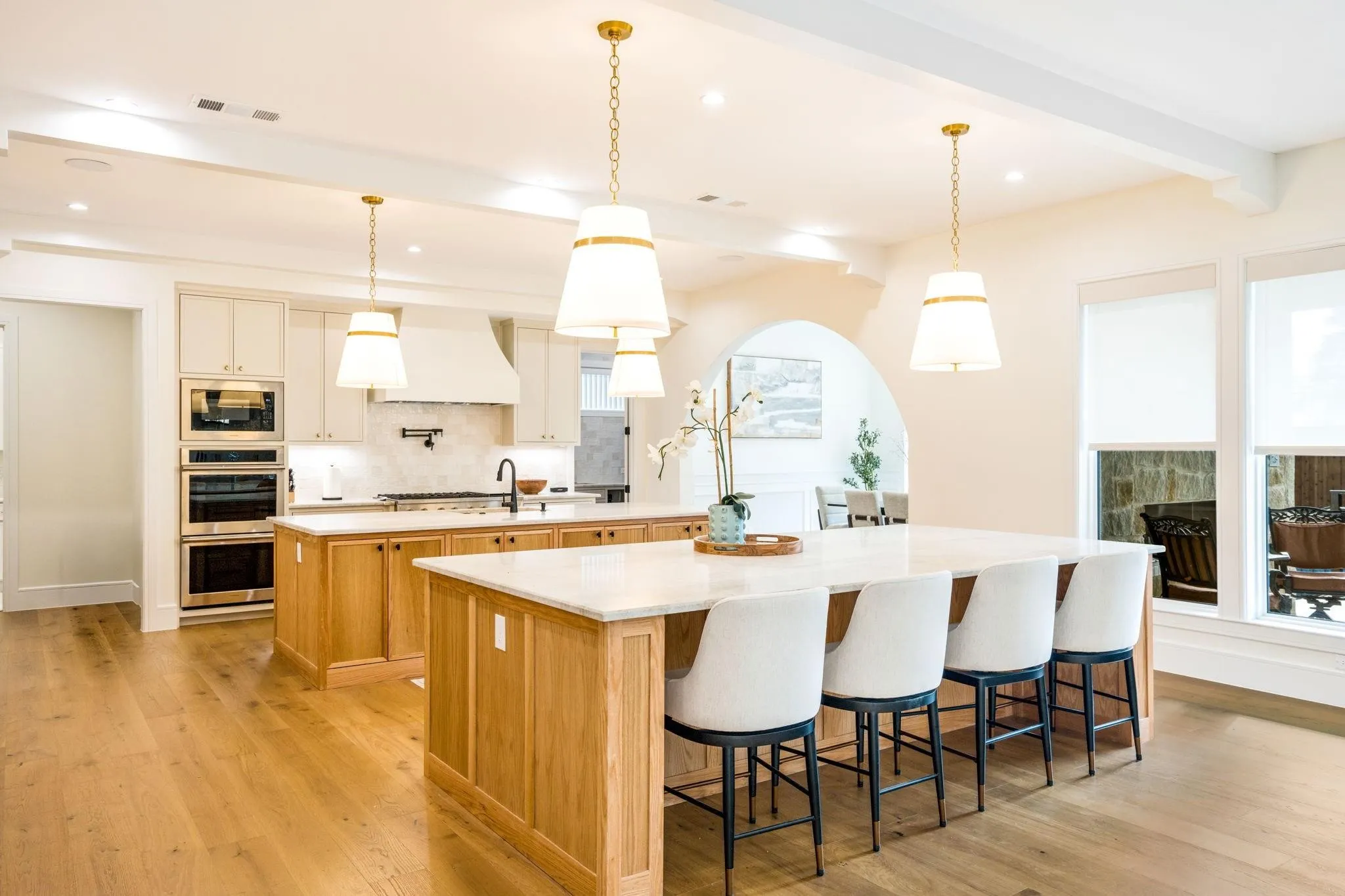 Kitchen featuring dual islands with light wood cabinetry, stone countertops, and pendant lighting