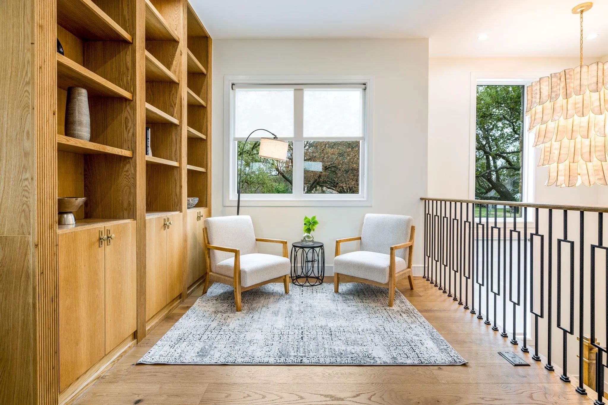 Built-in shelving with lower cabinetry, wood-finish flooring, and black metal balusters with geometric details