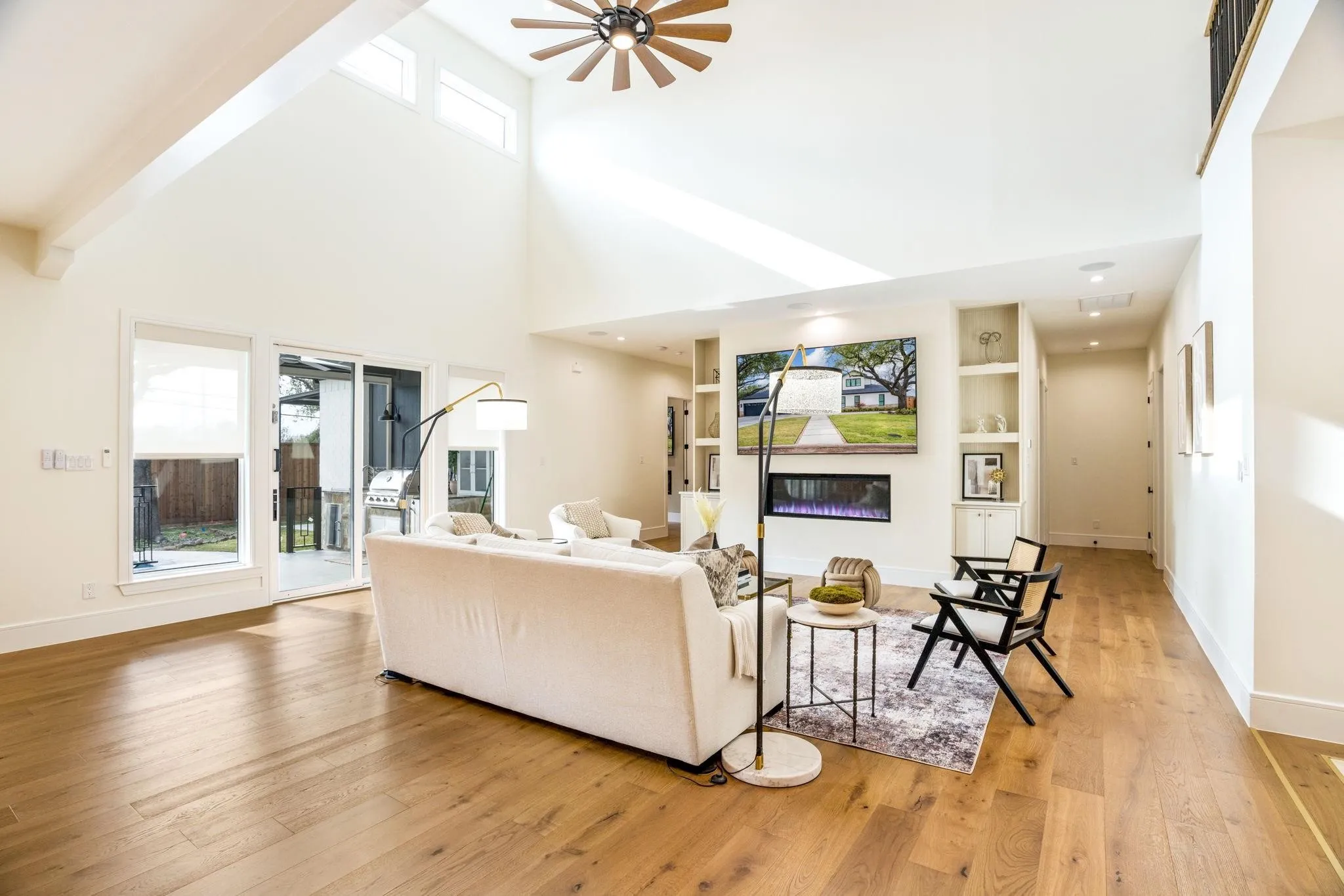 Vaulted ceiling, wood-finish flooring, built-in shelving, electric fireplace, and sliding glass door