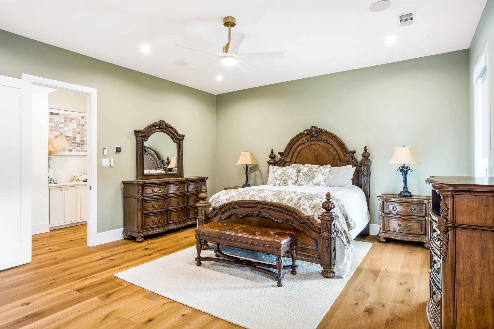 Hardwood flooring, recessed lighting, ceiling fan with brushed gold accents, light green wall paint, and a white sliding door