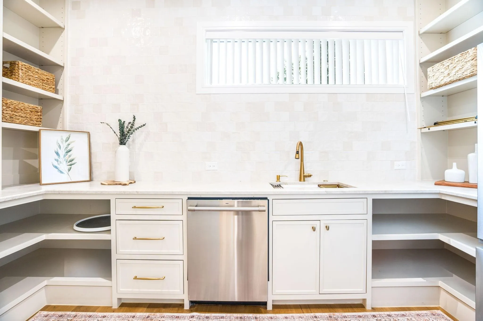 White cabinetry with gold-tone hardware, integrated sink with gold-tone faucet, and a stainless steel dishwasher
