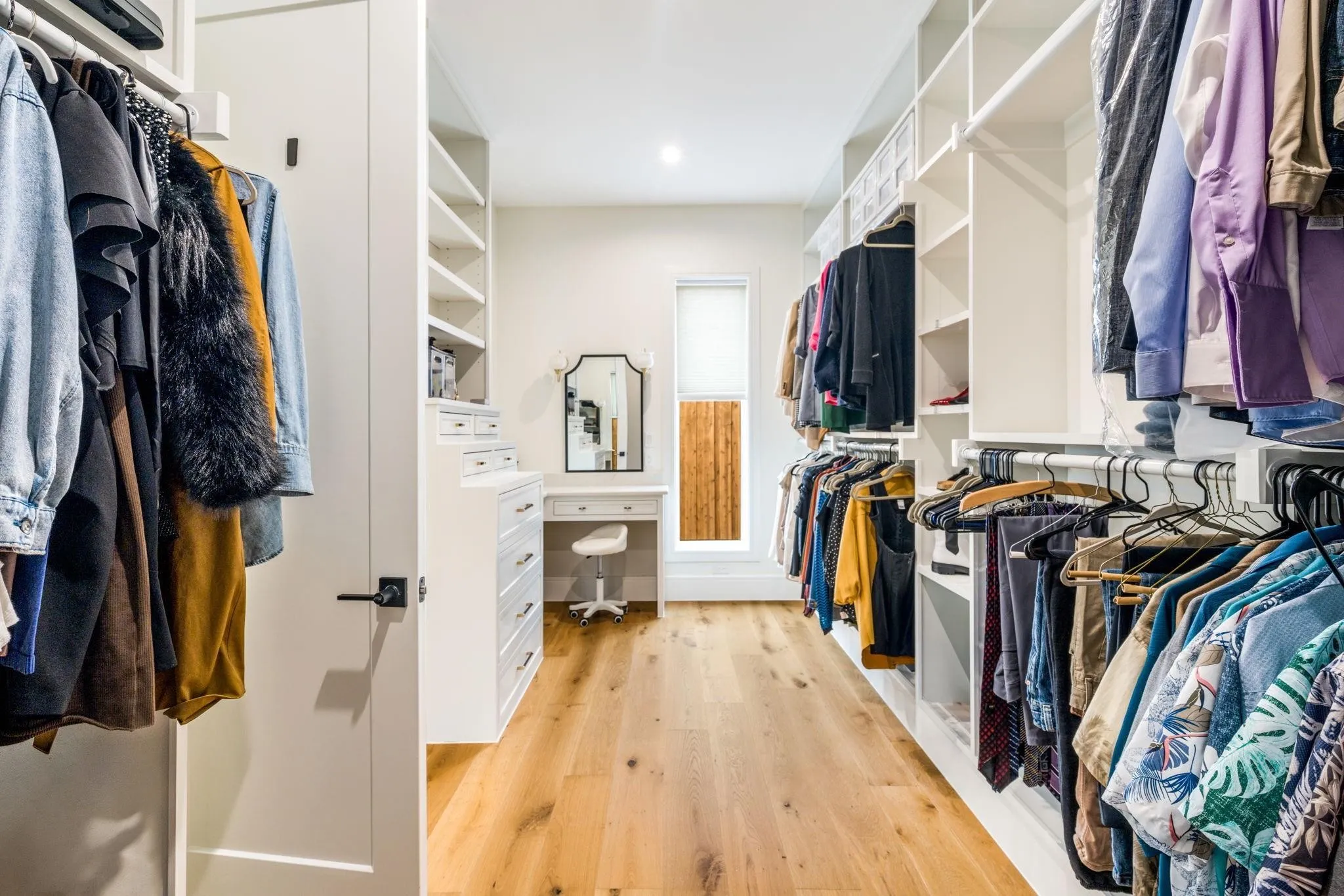 Custom built-in shelving, hardwood flooring, recessed lighting, built-in dresser, and an integrated vanity area