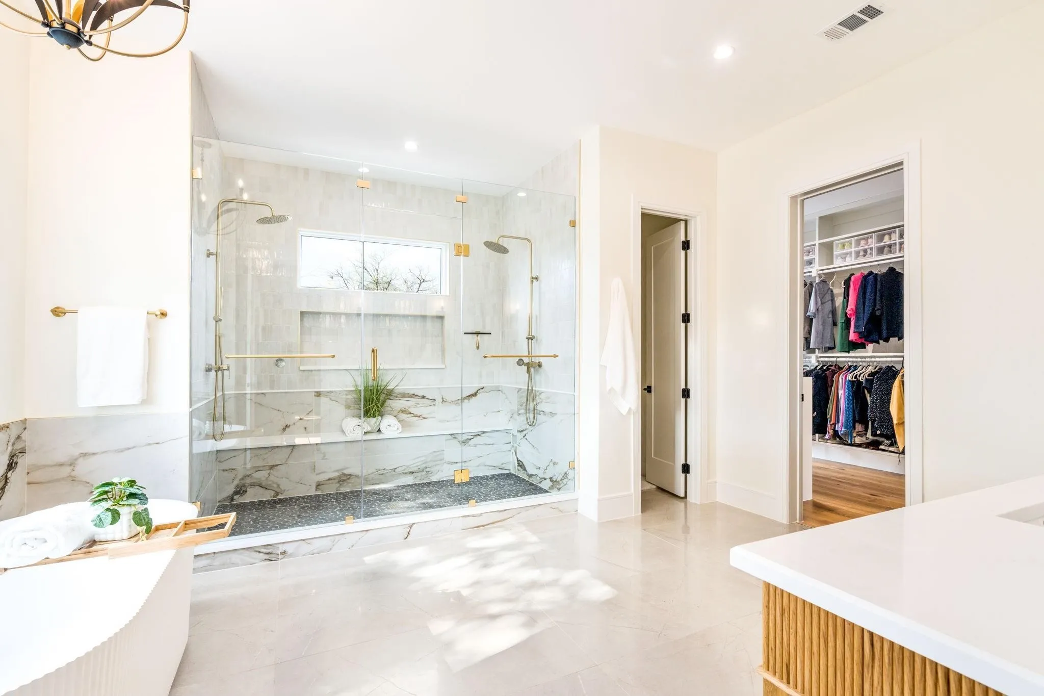 Spacious bathroom featuring a frameless glass shower enclosure, dual shower heads, a built-in shower bench, and a freestanding soaking tub