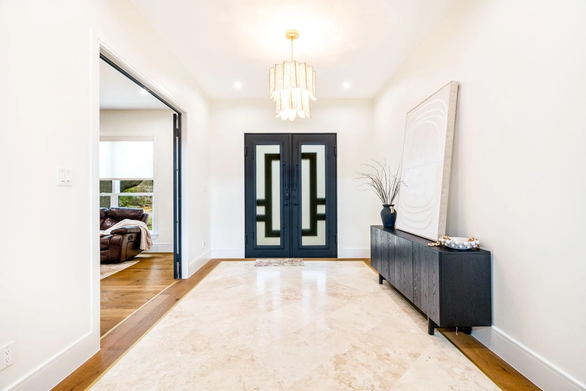 Entryway featuring a decorative chandelier, recessed lighting, double entry doors with geometric glass inserts, and stone tile flooring with a wood-finish border
