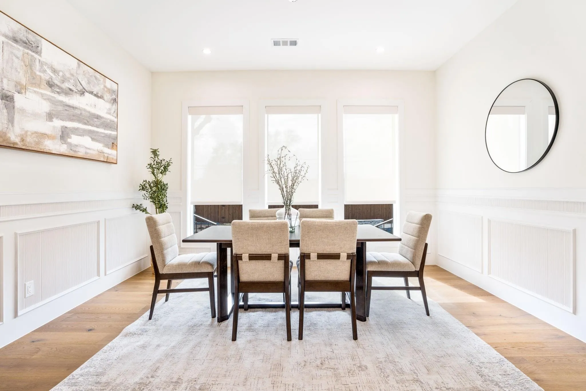 Recessed lighting illuminates the room with wainscoting details and wood-finish flooring