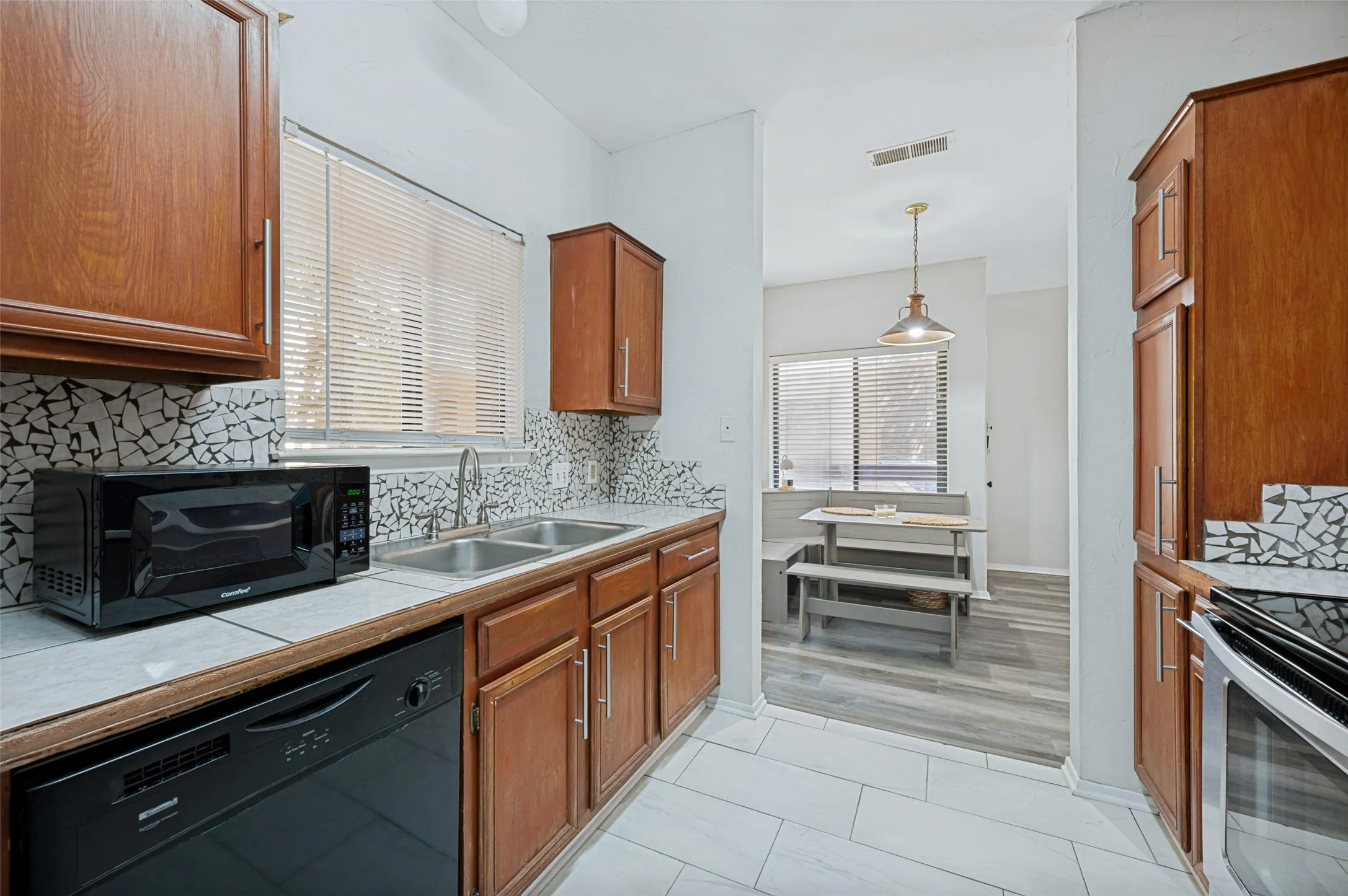 Kitchen featuring wood cabinetry, a double basin sink, and a patterned tile backsplash