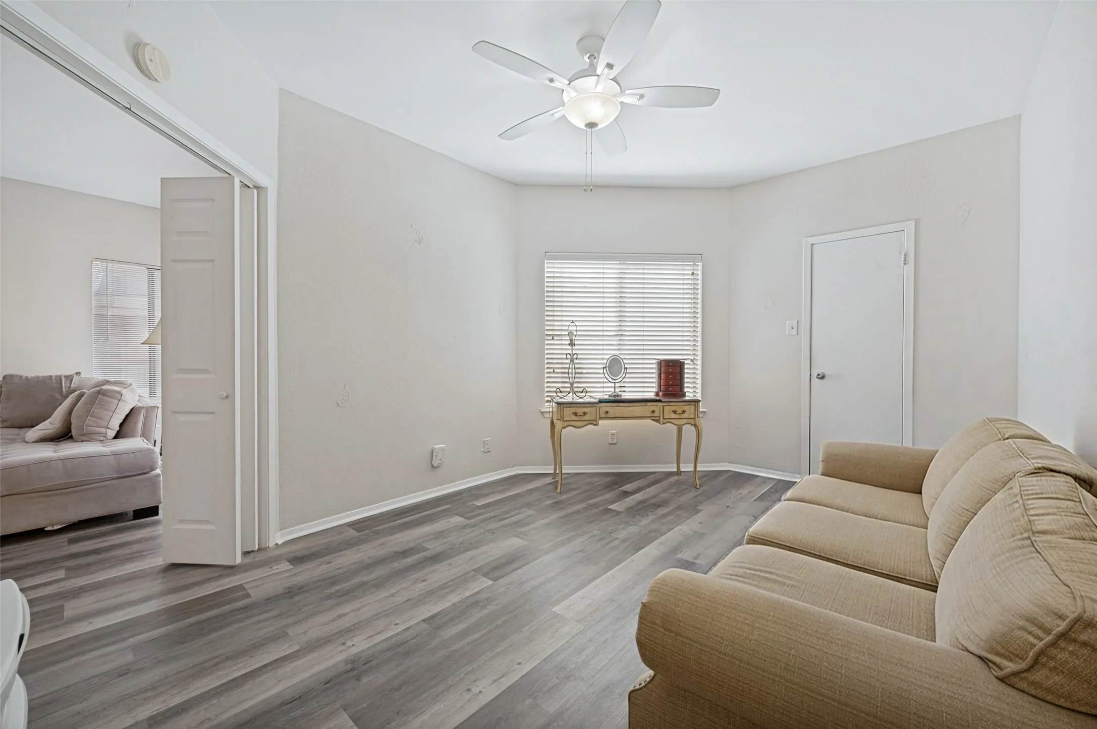 Wood-finish flooring throughout, ceiling fan with integrated lighting, and white interior doors