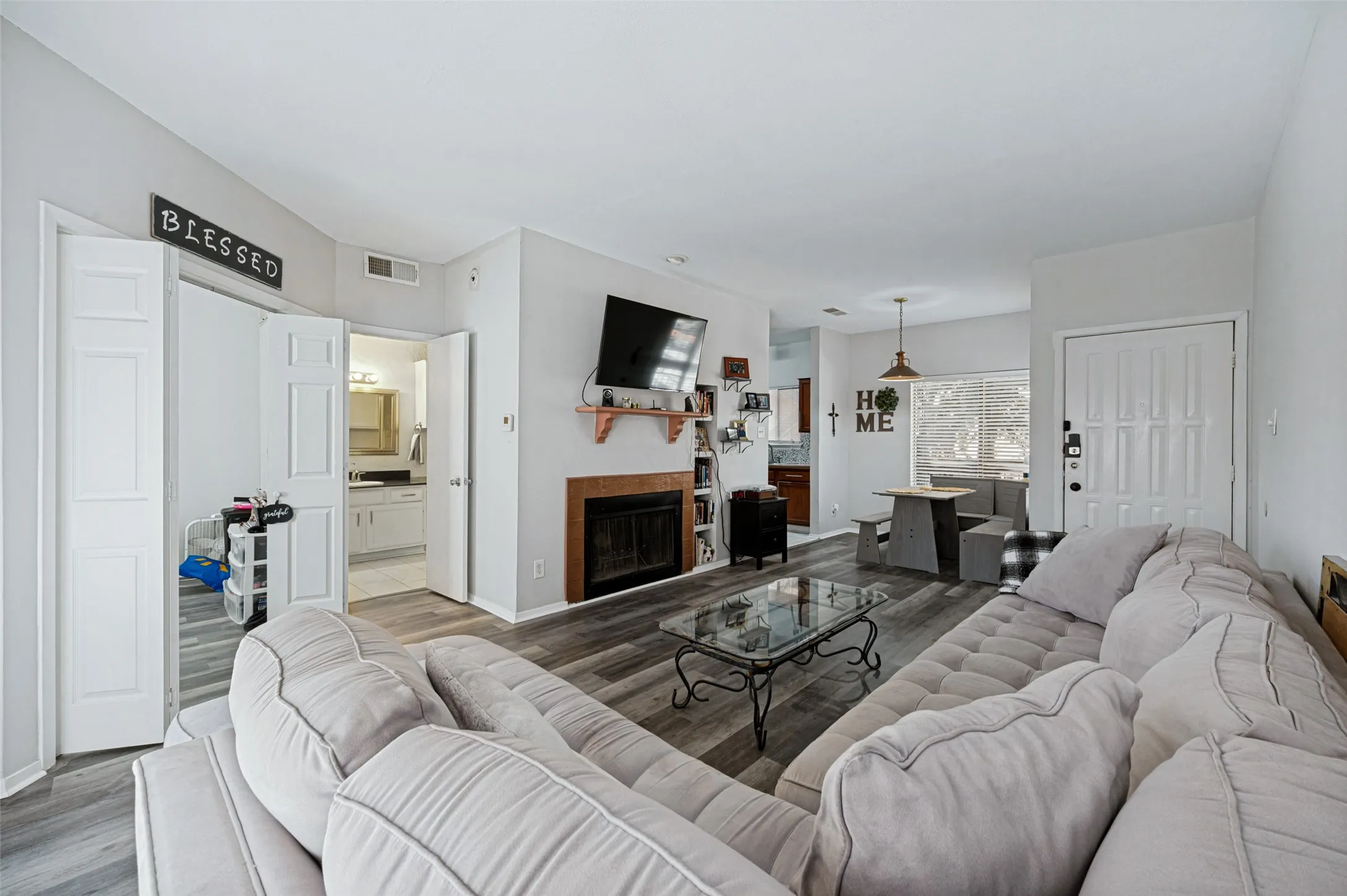 Wood-finish flooring throughout, fireplace with a wood mantle, recessed lighting, and a paneled entry door