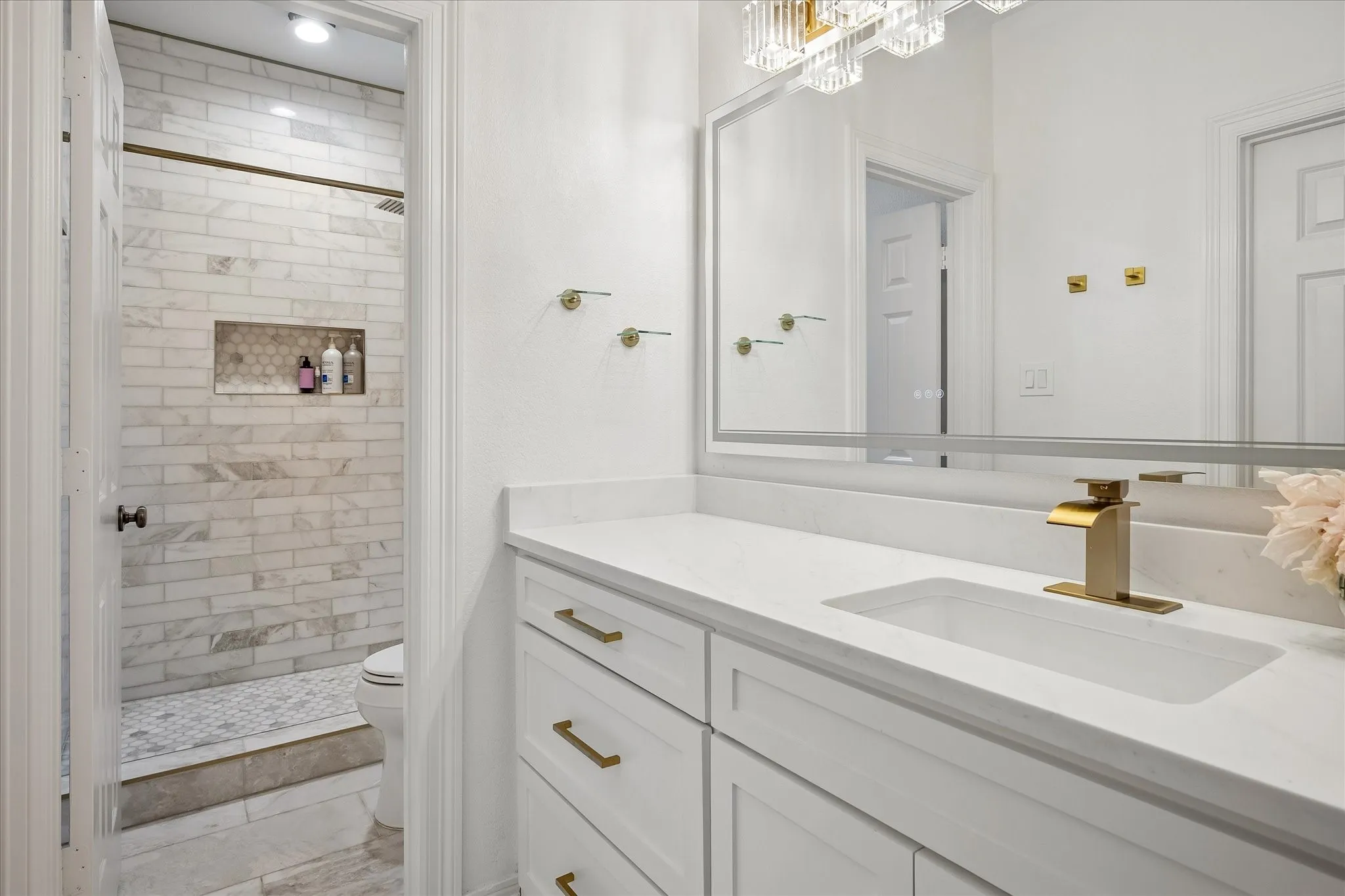 Spa-inspired primary bathroom featuring a floating vanity with dual sinks, white quartz countertop, and brass fixtures
