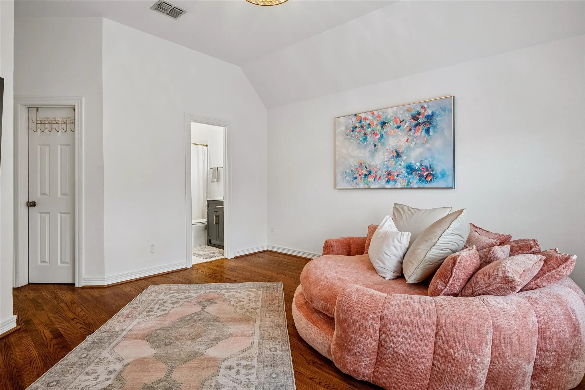 Spacious bedroom featuring hardwood flooring, arched ceiling detail, and abundant natural light