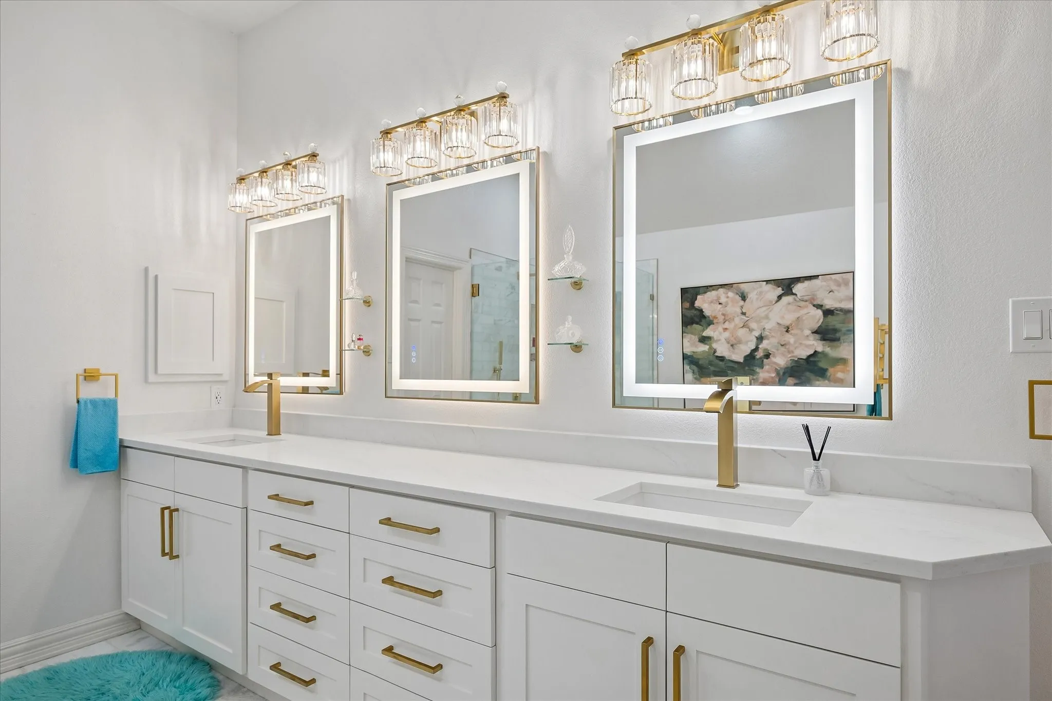Spa-inspired primary bathroom showcasing a lengthy white vanity with dual integrated sinks, brushed brass hardware, and ample storage cabinetry