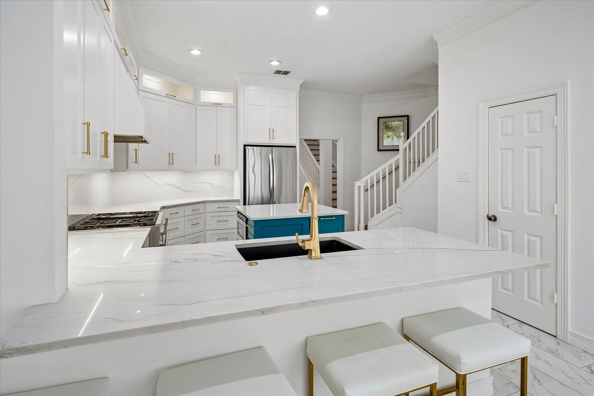 Kitchen featuring white cabinetry, gold-tone hardware, a central island with a contrasting finish, and a gold-tone faucet