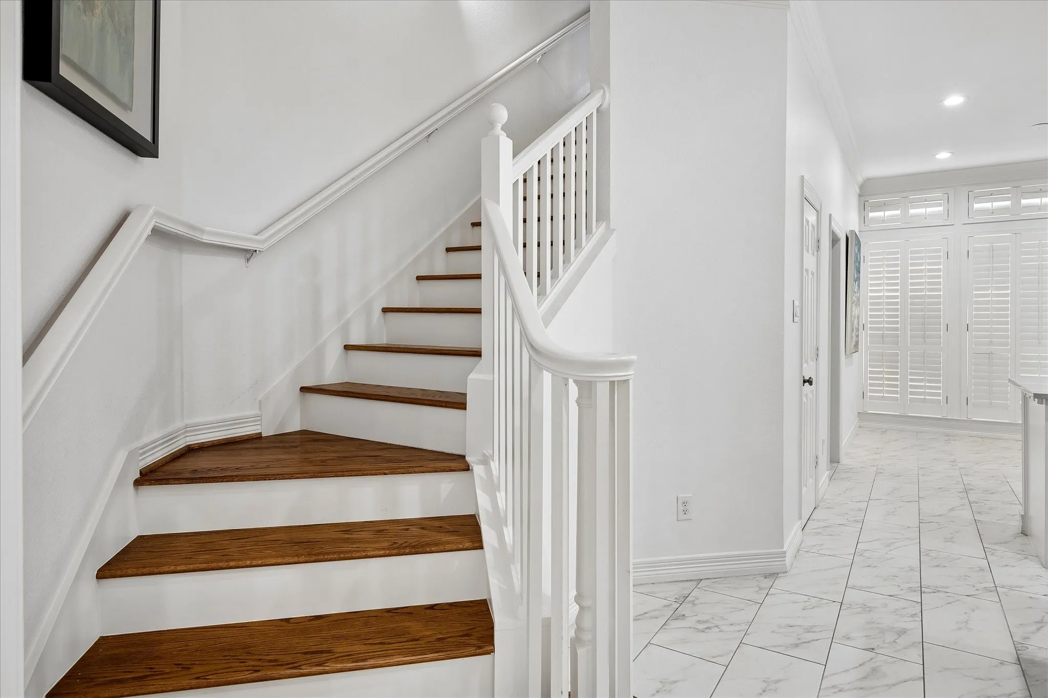 Staircase with wood-finish treads and white risers, white balusters, and a white handrail