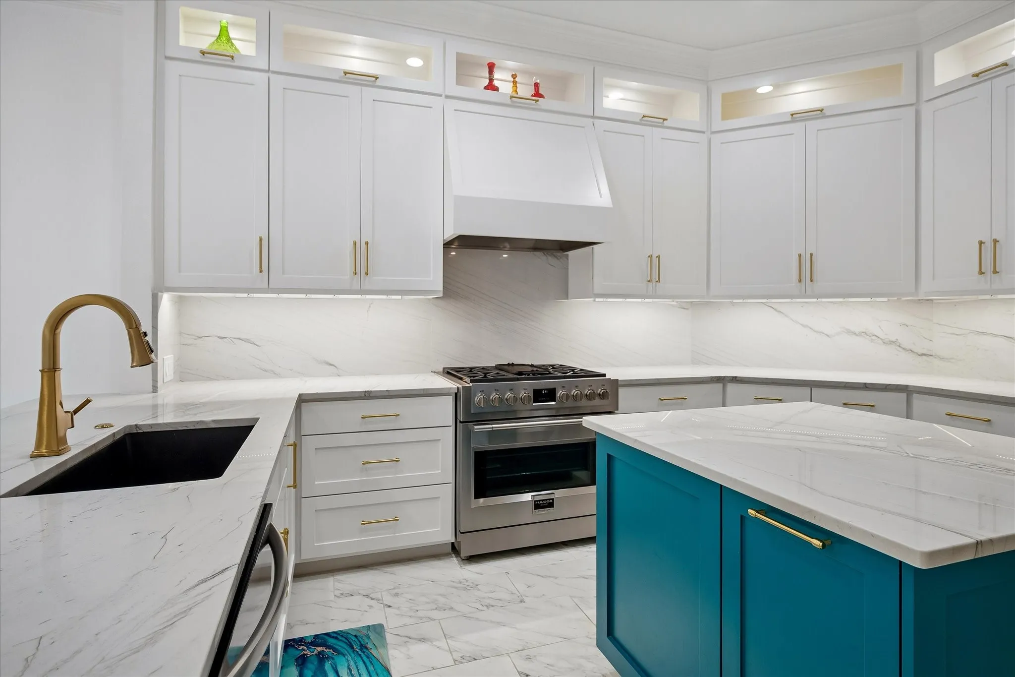 Sophisticated kitchen featuring white cabinetry with brushed nickel hardware, marble-finish countertops, and a teal-finished island with matching countertop surface
