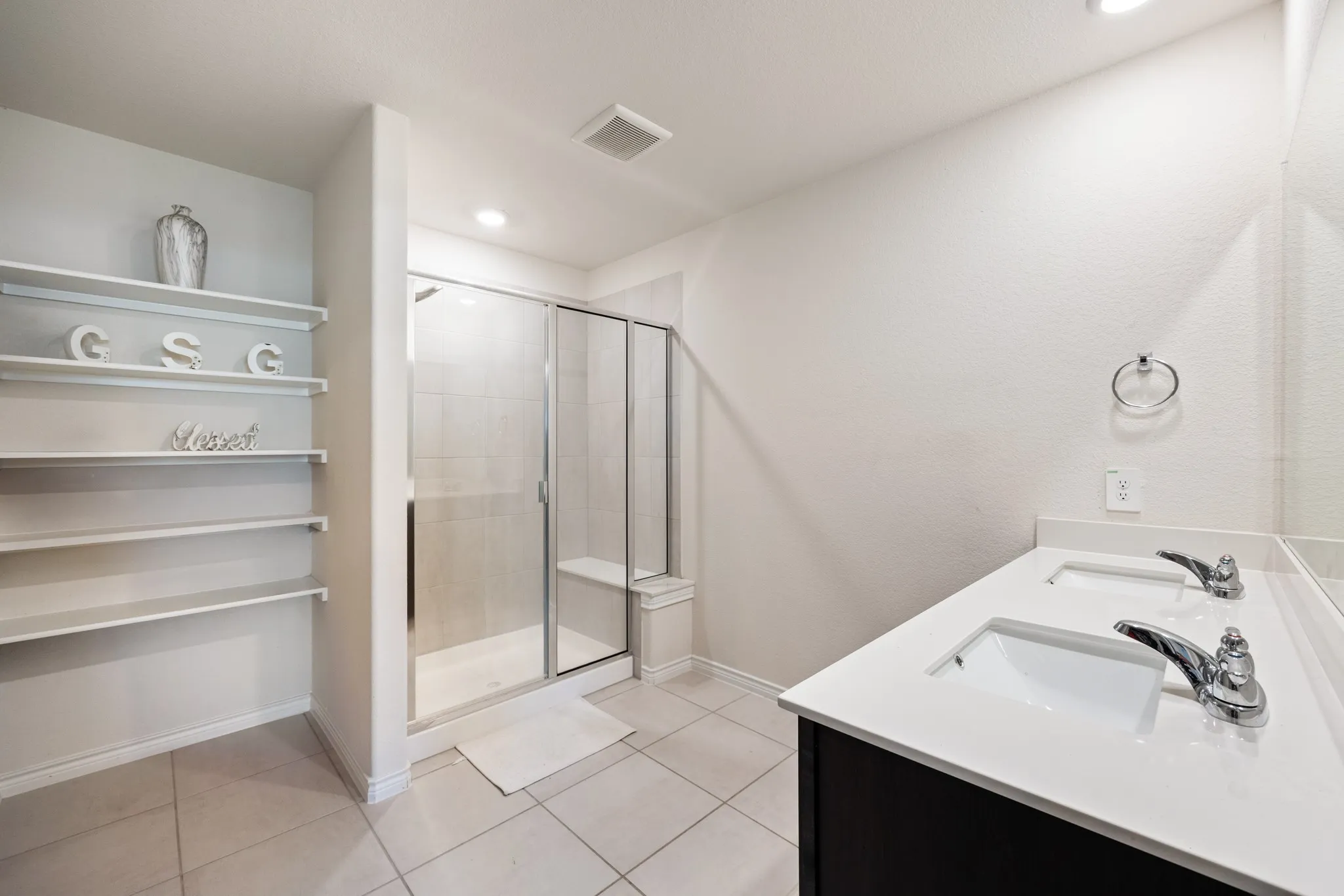 Dual undermount sinks with chrome faucets, white countertop, and dark wood-finish vanity