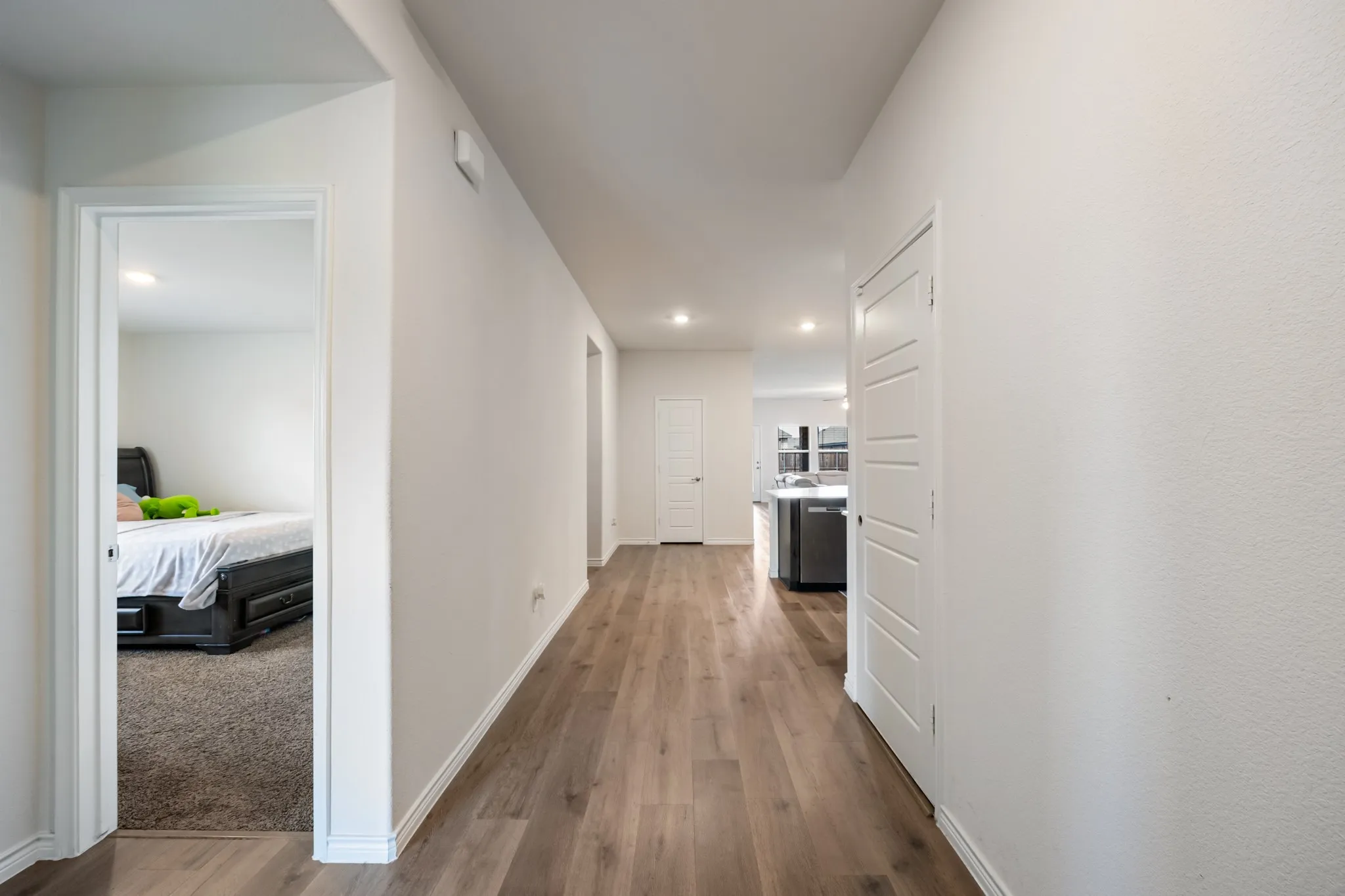 Wood-finish flooring, white walls, recessed lighting, and a white interior door with horizontal paneling