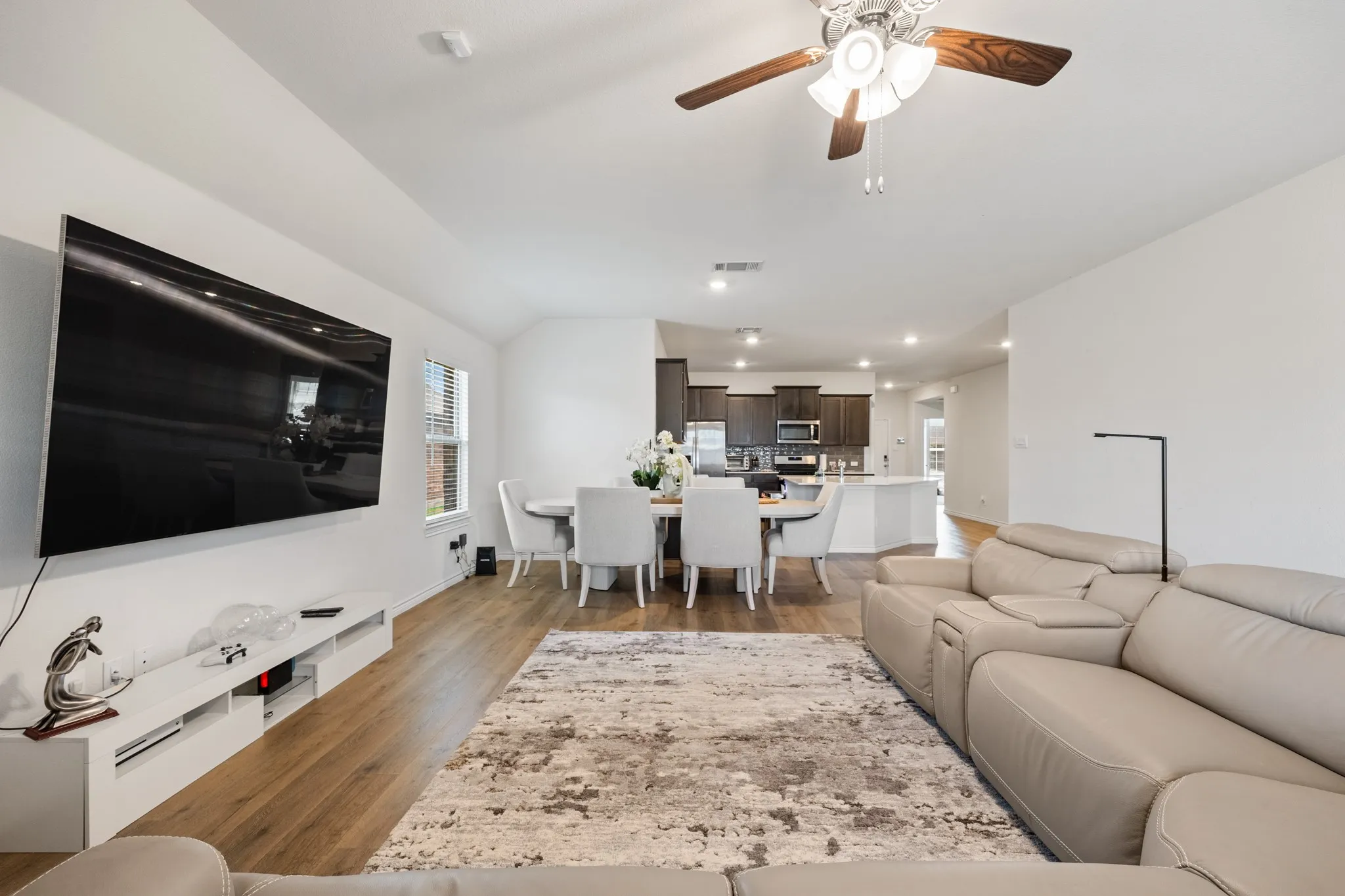 Open-concept living space featuring wood-finish flooring, a ceiling fan with light fixture, and recessed lighting