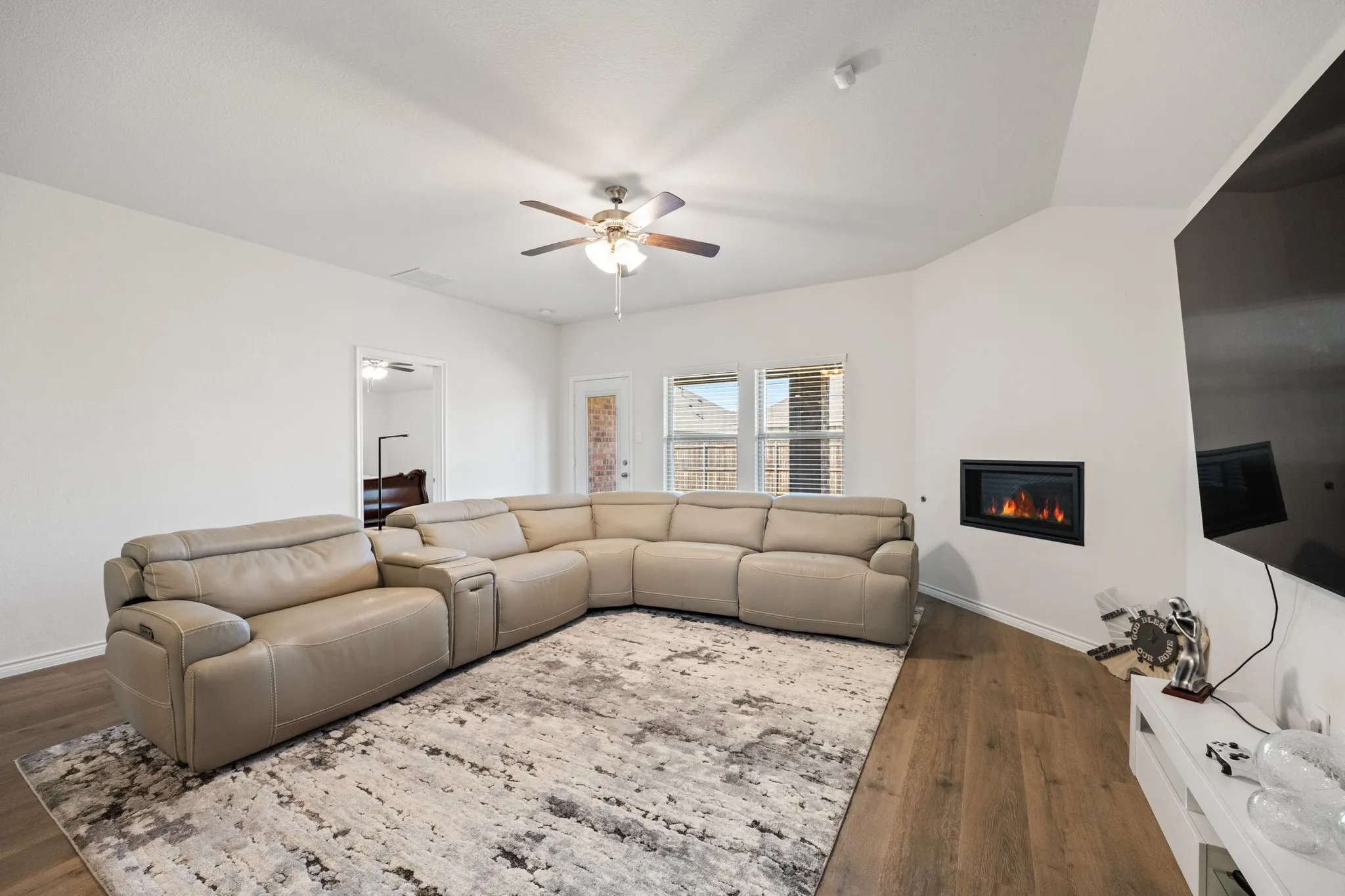 Vaulted ceiling, wood-finish flooring, recessed fireplace, ceiling fan, and multiple windows
