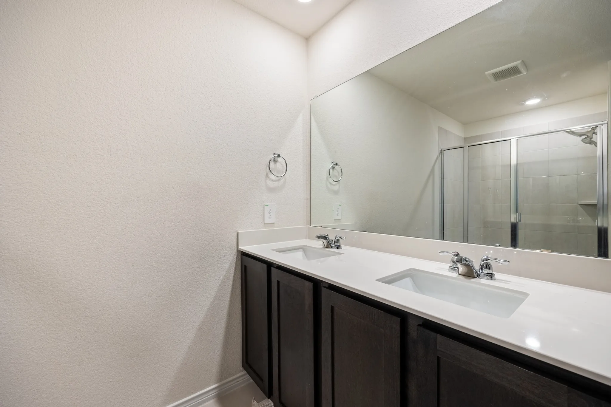Dual undermount sinks with chrome fixtures, expansive countertop space, and dark wood-finish cabinetry