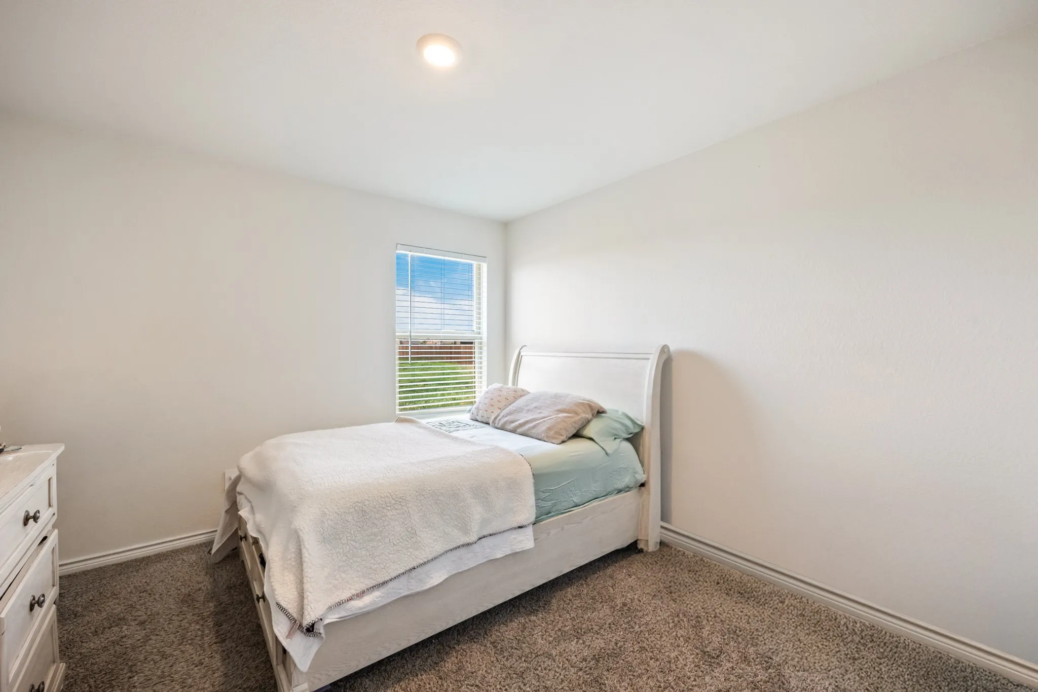 Recessed ceiling lighting, textured wall finishes, and a single window with blinds