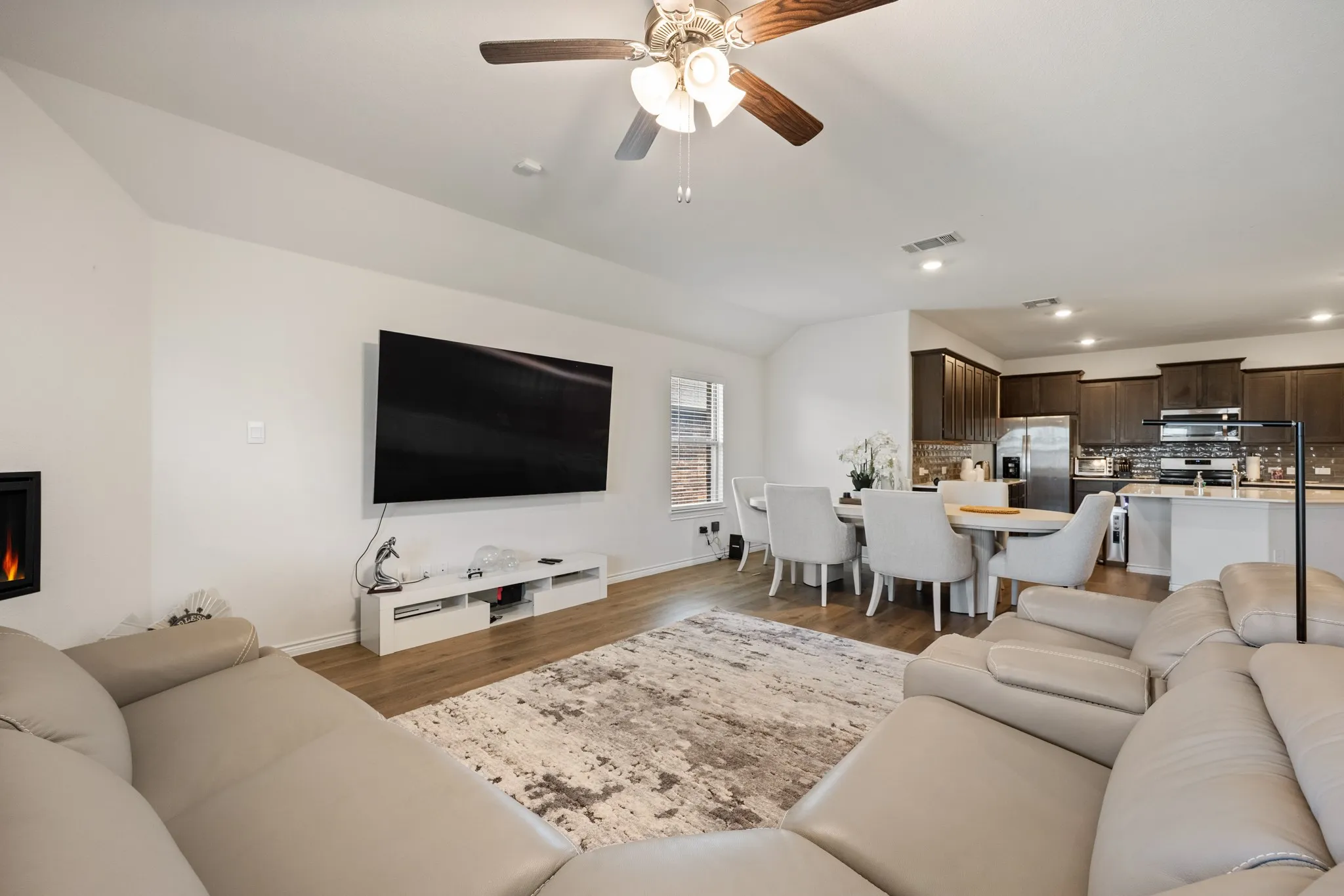 Vaulted ceiling with a ceiling fan, wood-finish flooring, recessed lighting, and an electric fireplace