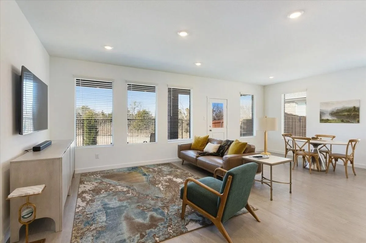 Open-concept living area with light-toned wood-finish flooring, recessed lighting, and multiple windows