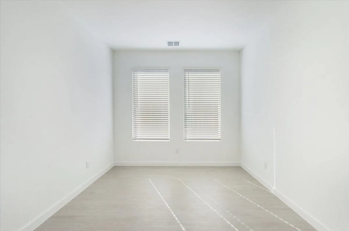 Crisp white walls, two windows with blinds, wood-finish flooring, and recessed lighting